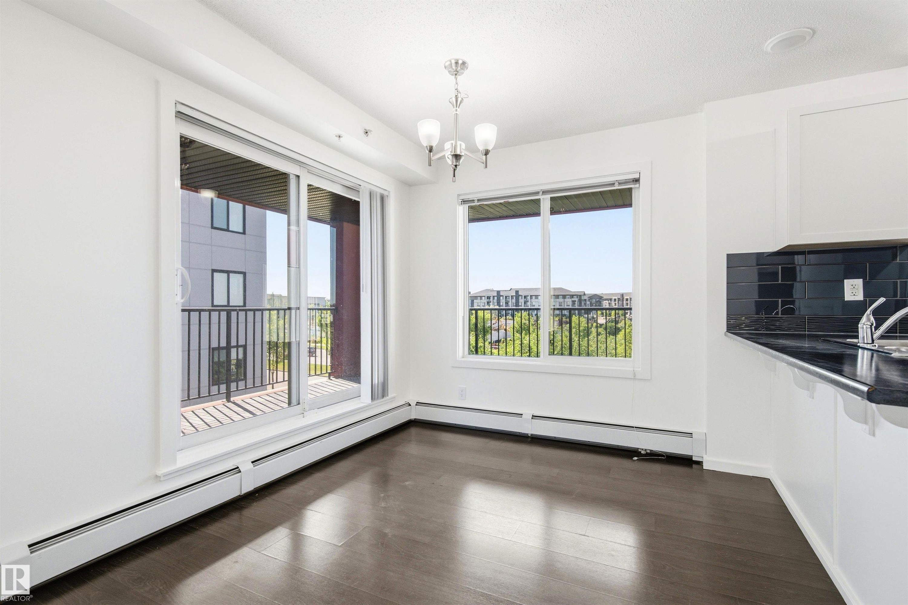 Open-concept living area featuring dark wood-finish flooring and white walls - 435 5515 7 Avenue, Edmonton, AB
