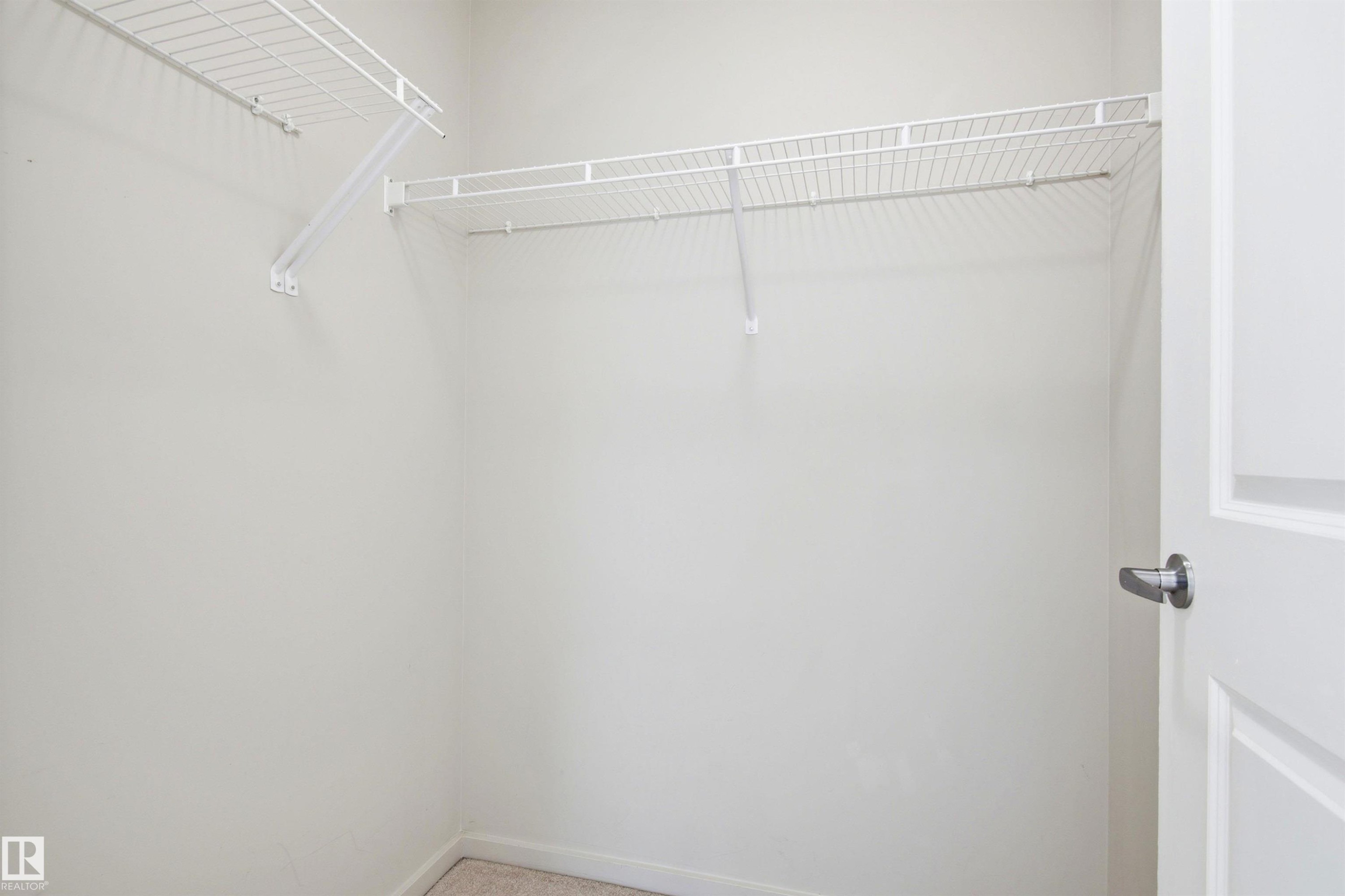 Walk-in closet featuring wire shelving, integrated hanging rods, and light-toned wall paint - 435 5515 7 Avenue, Edmonton, AB