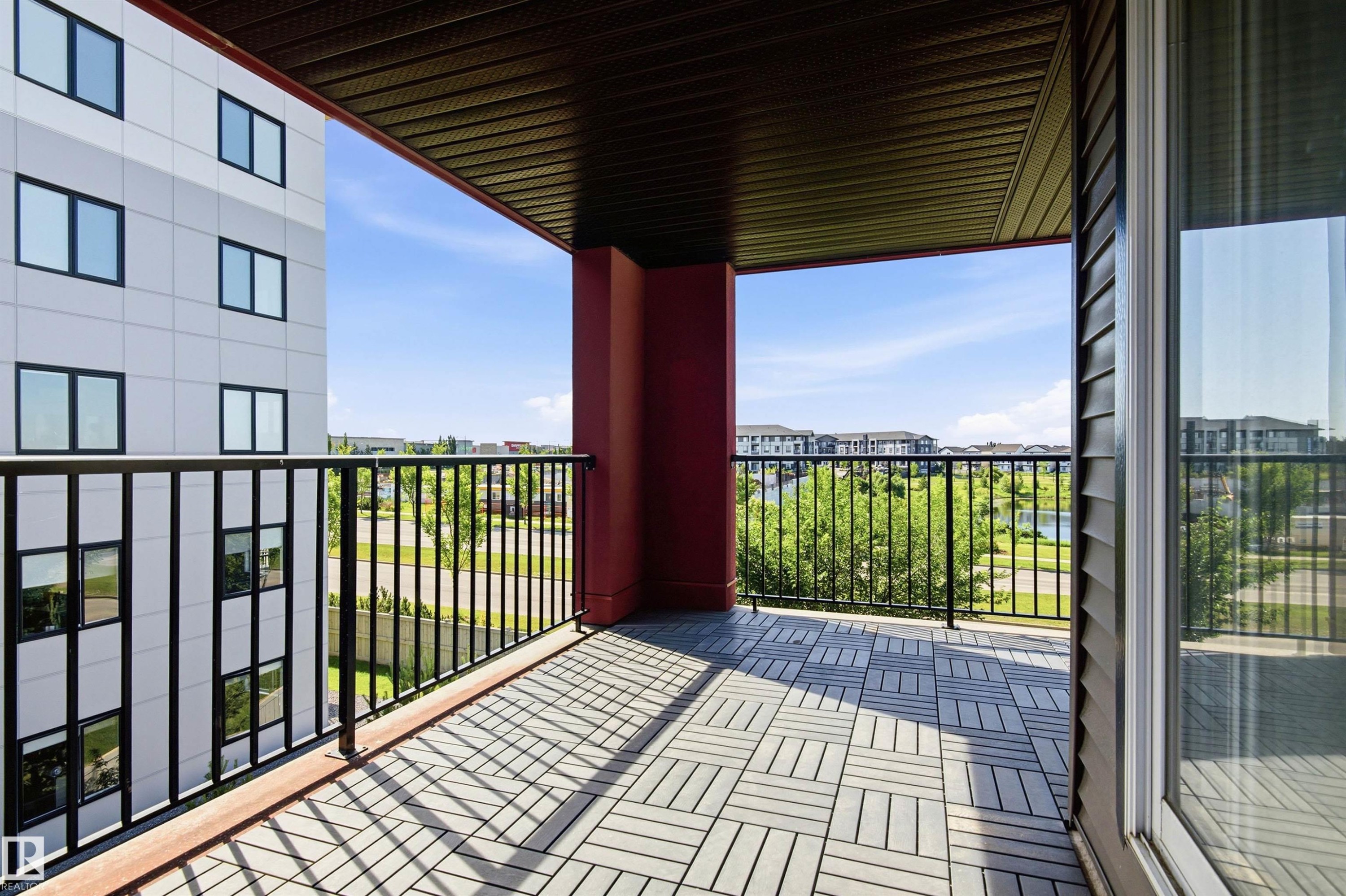 Private balcony featuring composite decking, black metal railing, and an exterior wall with horizontal siding - 435 5515 7 Avenue, Edmonton, AB