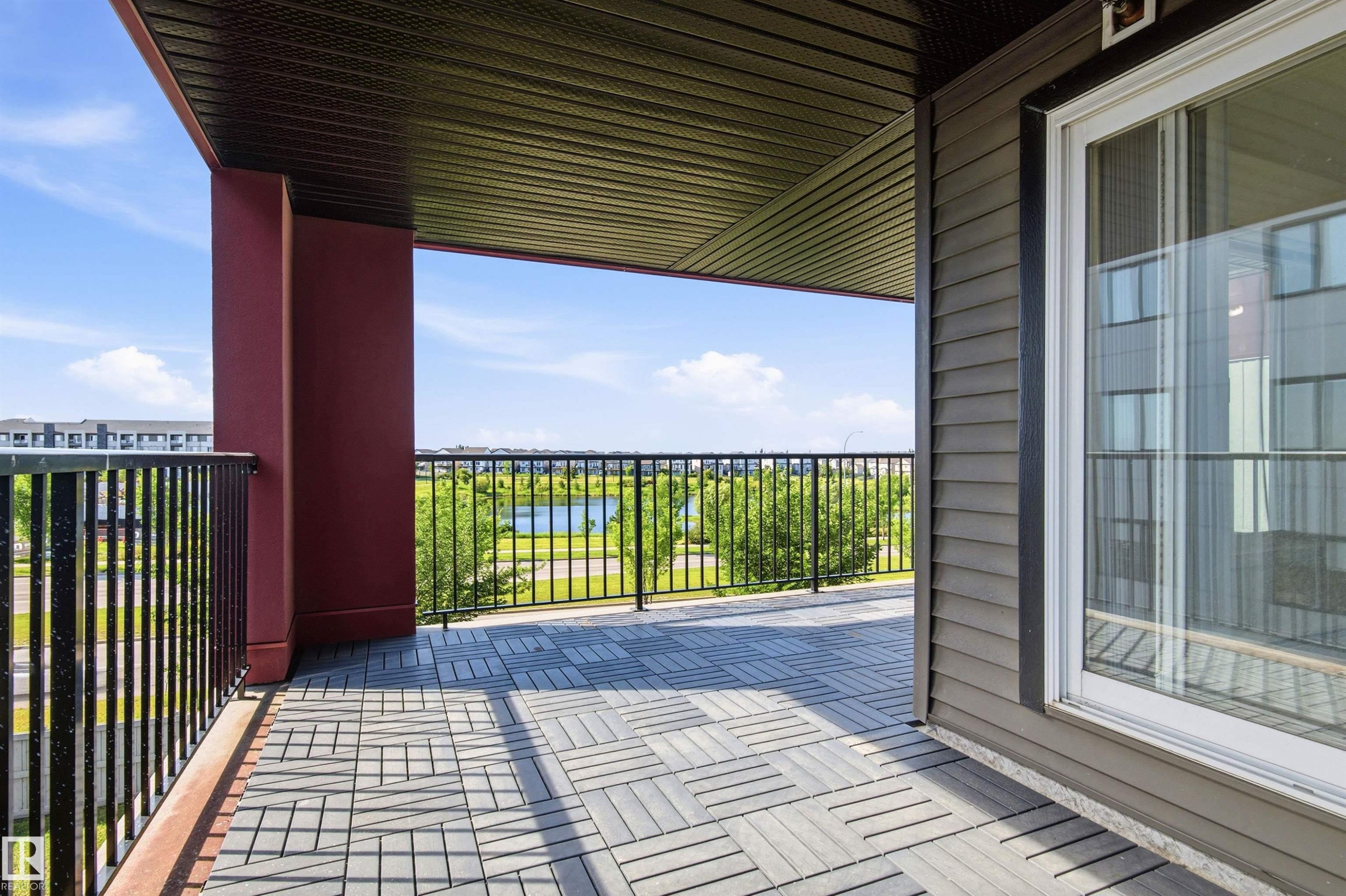 Spacious outdoor balcony with a patterned tile floor, black metal railings, and a solid red support column - 435 5515 7 Avenue, Edmonton, AB