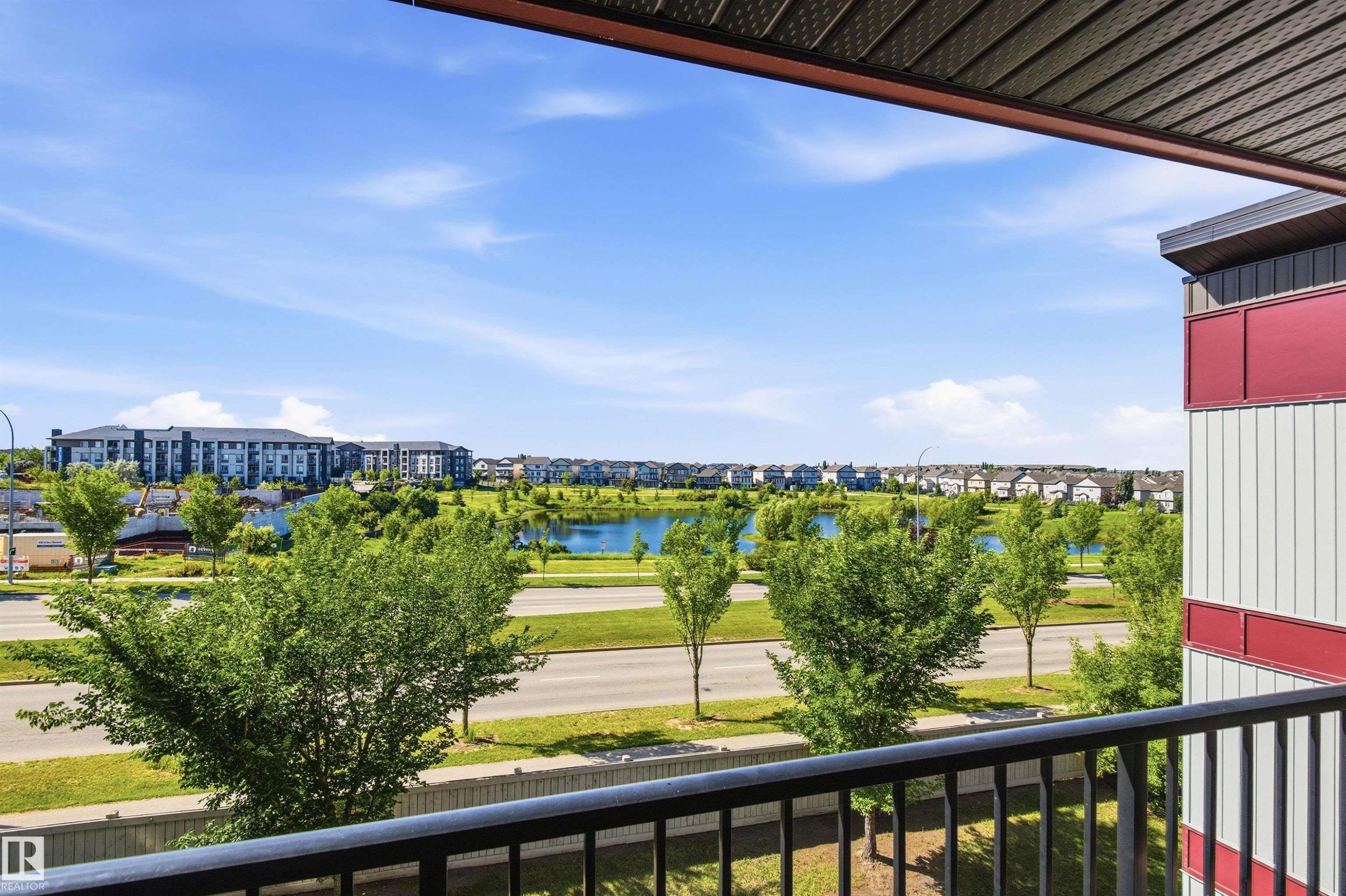 Balcony with black metal railing, offering expansive landscape and water feature - 435 5515 7 Avenue, Edmonton, AB