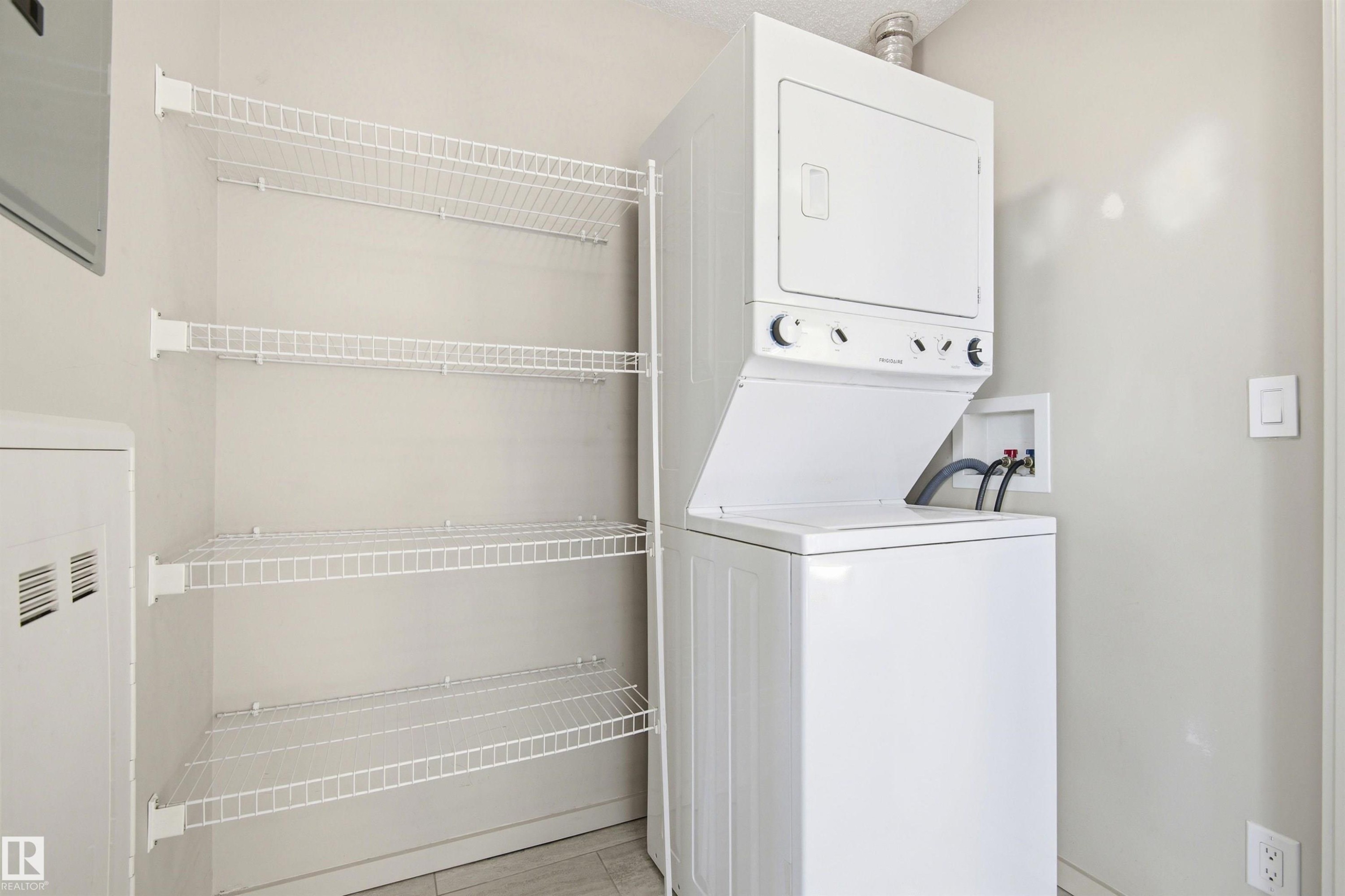 Dedicated laundry area featuring a white Frigidaire stacked washer and dryer unit - 435 5515 7 Avenue, Edmonton, AB