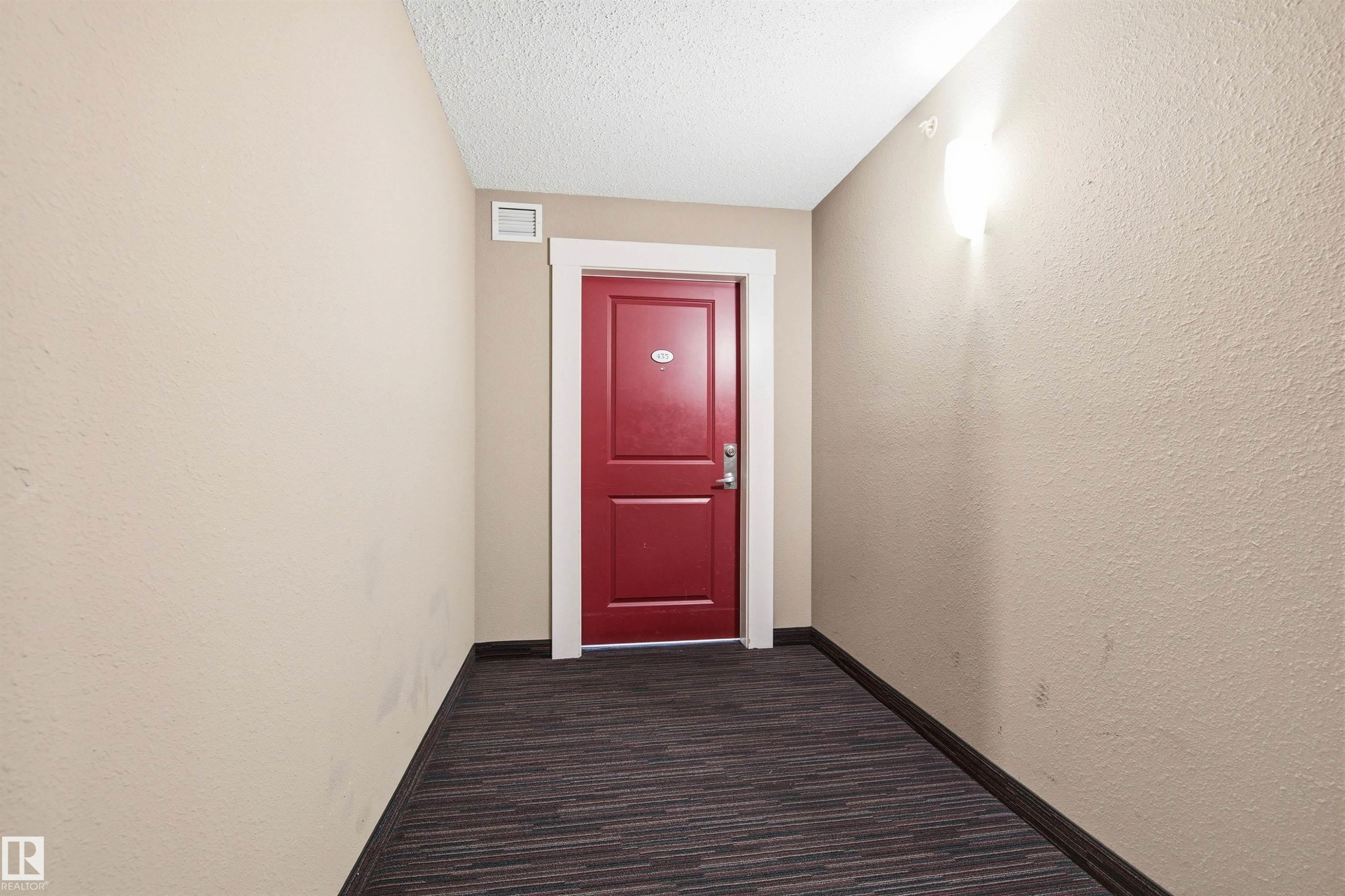 Vibrant red entry door with white trim, set against neutral wall tones - 435 5515 7 Avenue, Edmonton, AB