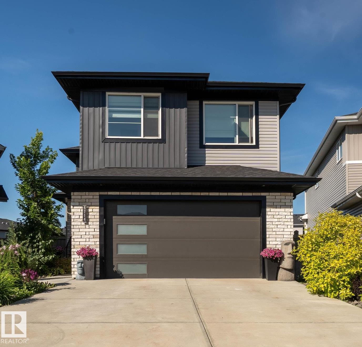 Contemporary two-story residence featuring a dark gray and beige vertical siding facade - 4714 Charles Bay Bay, Edmonton, AB