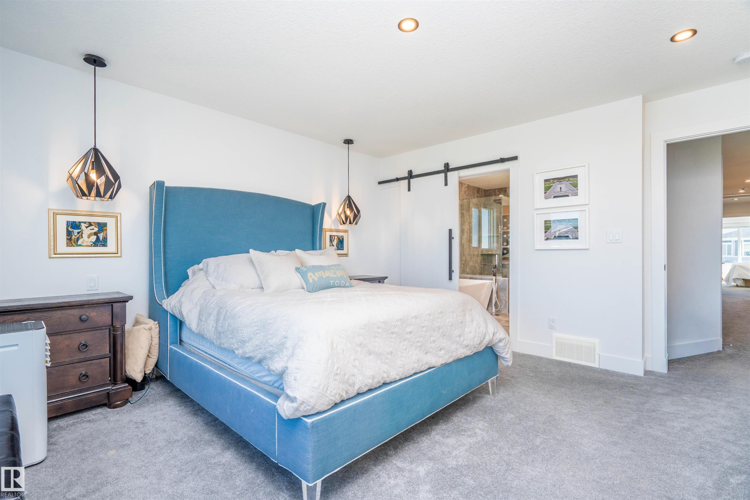 Spacious room featuring neutral carpeting, recessed lighting, and modern pendant light fixtures - 4714 Charles Bay Bay, Edmonton, AB