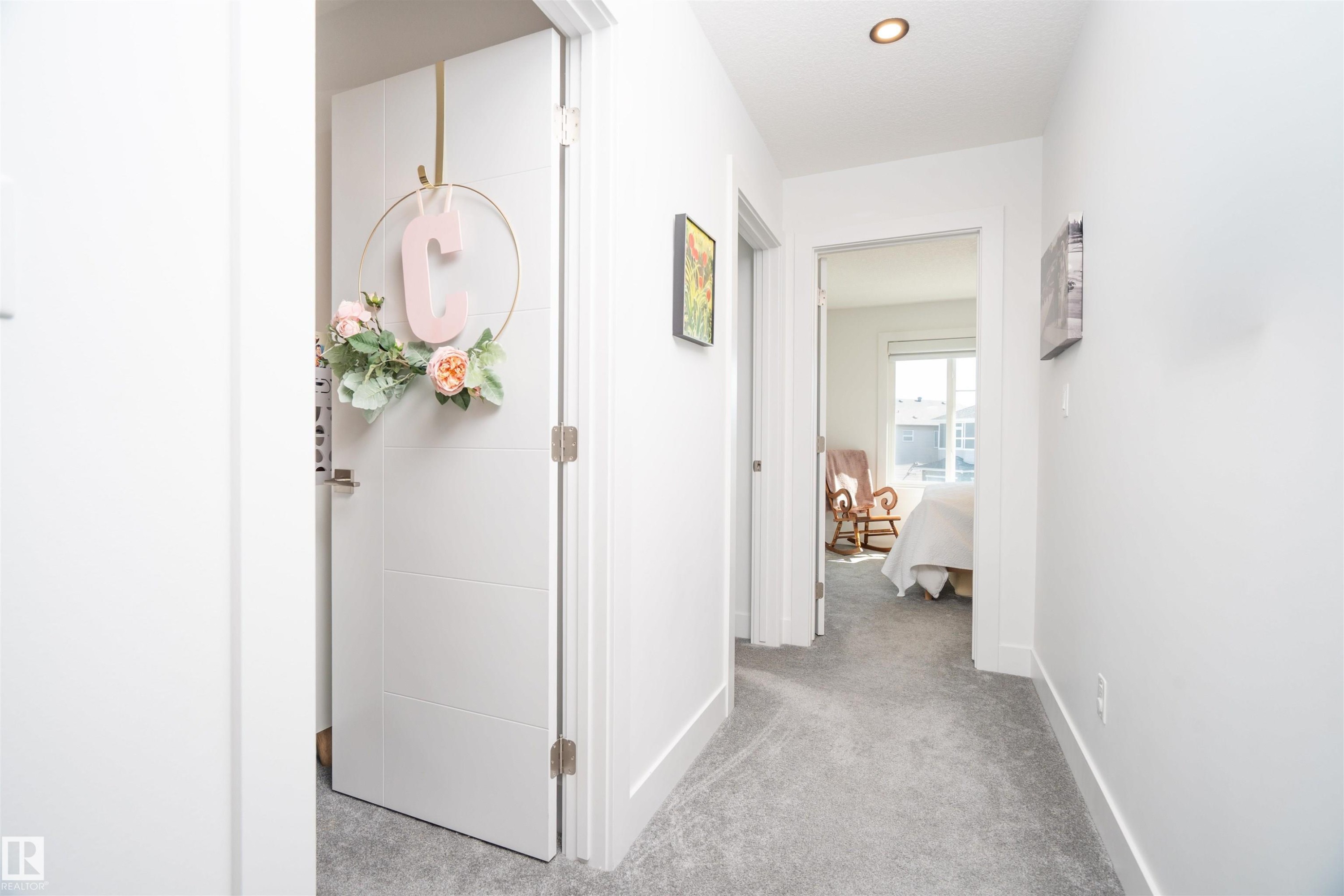 Hallway featuring light gray carpeting, white baseboards, and bright white walls - 4714 Charles Bay Bay, Edmonton, AB