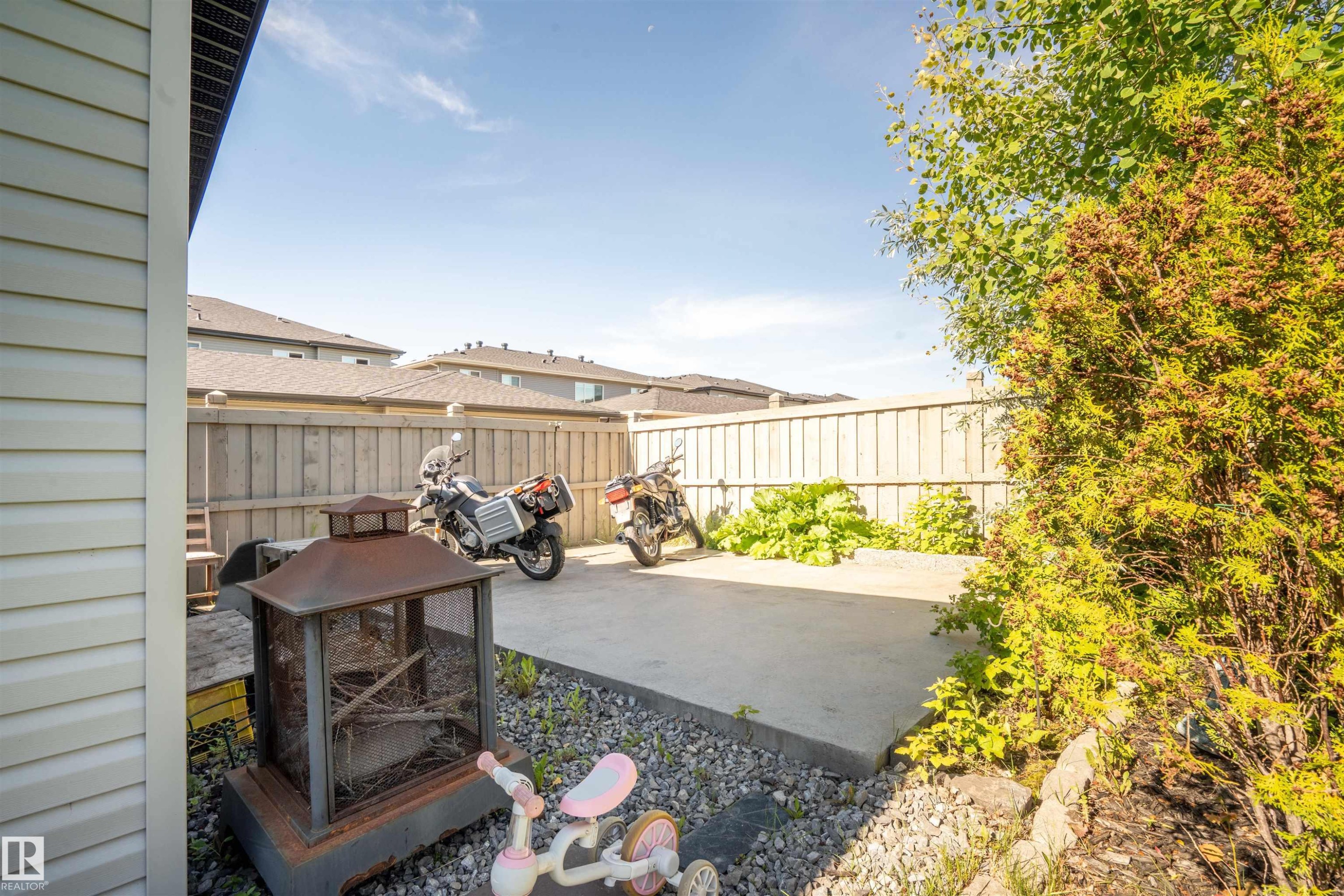 Backyard featuring a concrete patio, wood privacy fence, and mature landscaping - 4714 Charles Bay Sw, Edmonton, AB - Outdoor