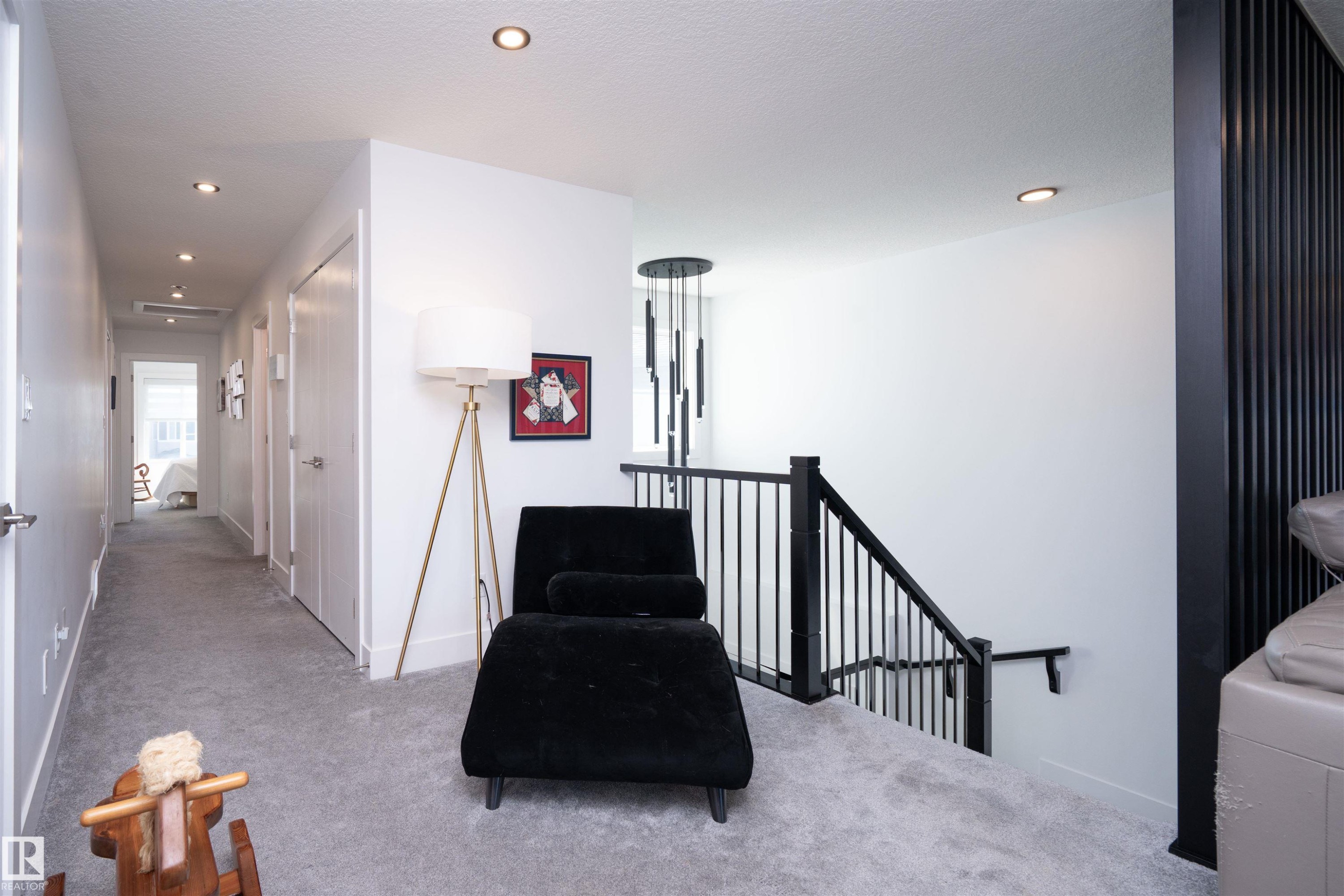 Upper-level landing featuring light grey carpeting, recessed lighting, and a contemporary black metal baluster staircase - 4714 Charles Bay Bay, Edmonton, AB