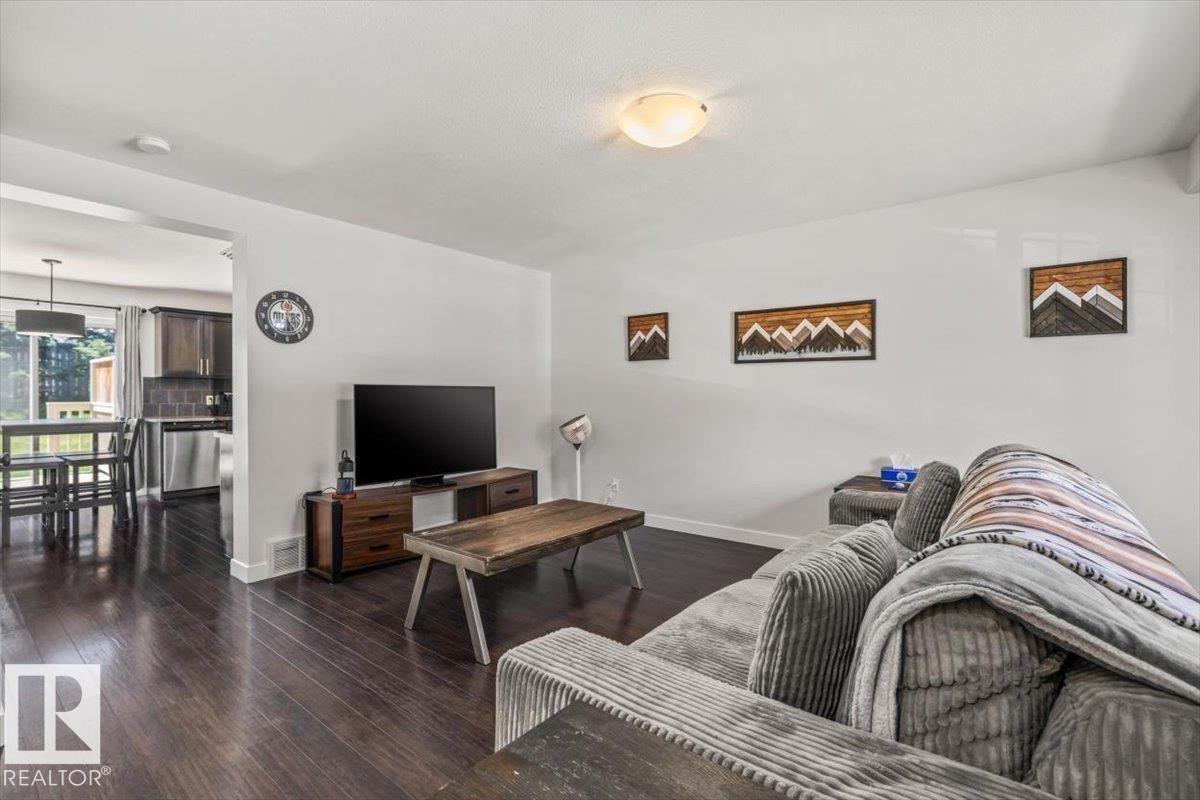 Spacious living area featuring dark wood-finish flooring, white walls, and a ceiling-mounted light fixture - 125 Birchwood Close, Devon, AB