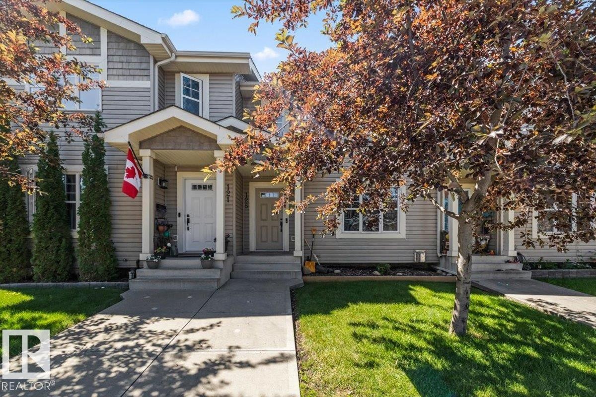 Front exterior featuring light-colored siding, a covered porch entrance, and a concrete walkway - 125 Birchwood Close, Devon, AB