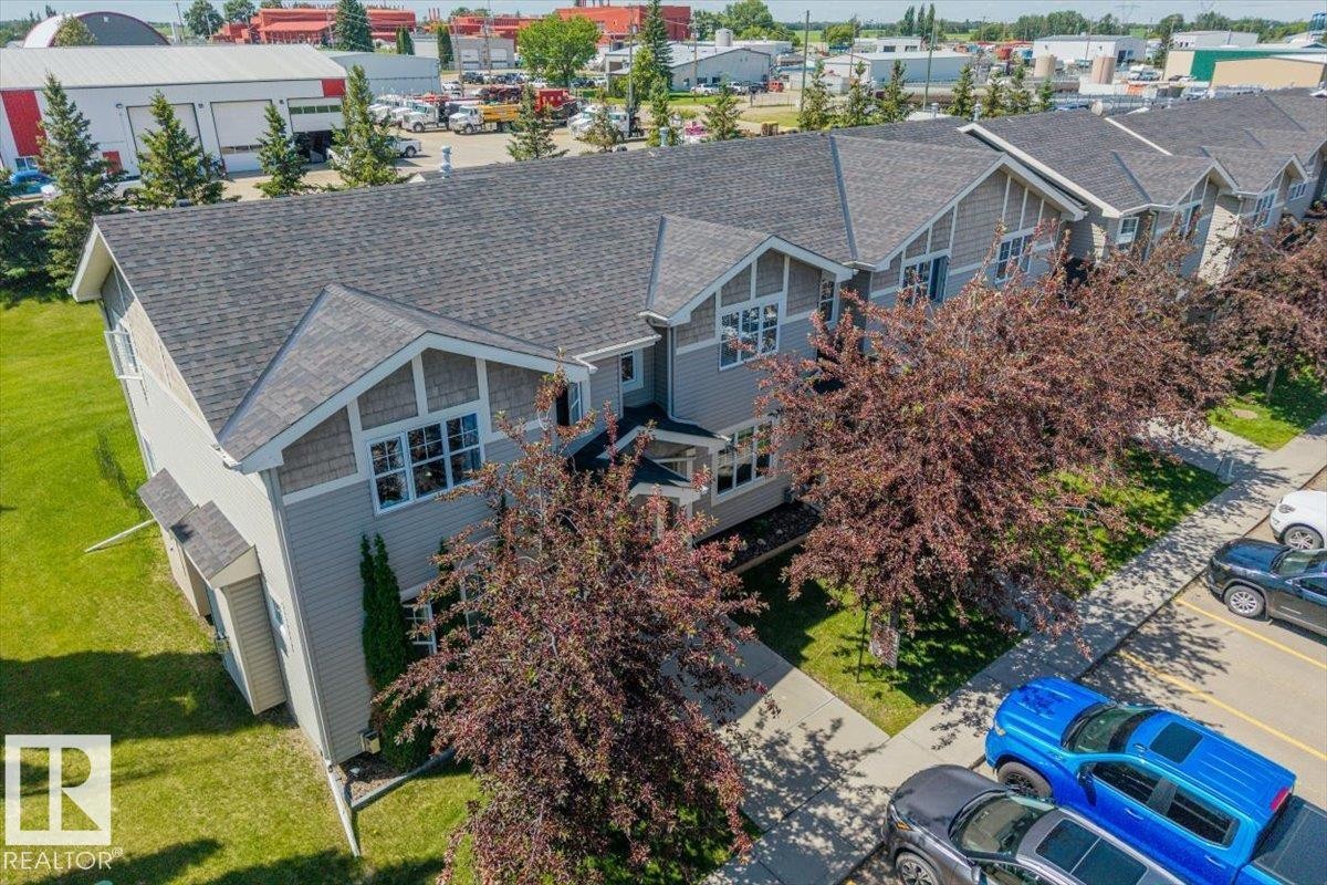 Modern townhome exterior featuring light gray siding, dark shingle roofing, and decorative gables with shingle accents - 125 Birchwood Close, Devon, AB