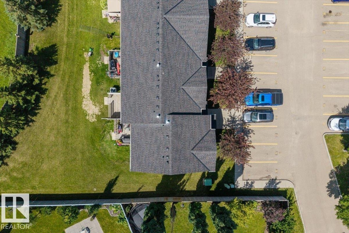 Multi-unit residential building featuring a dark shingle roof and individual rear patios - 125 Birchwood Close, Devon, AB