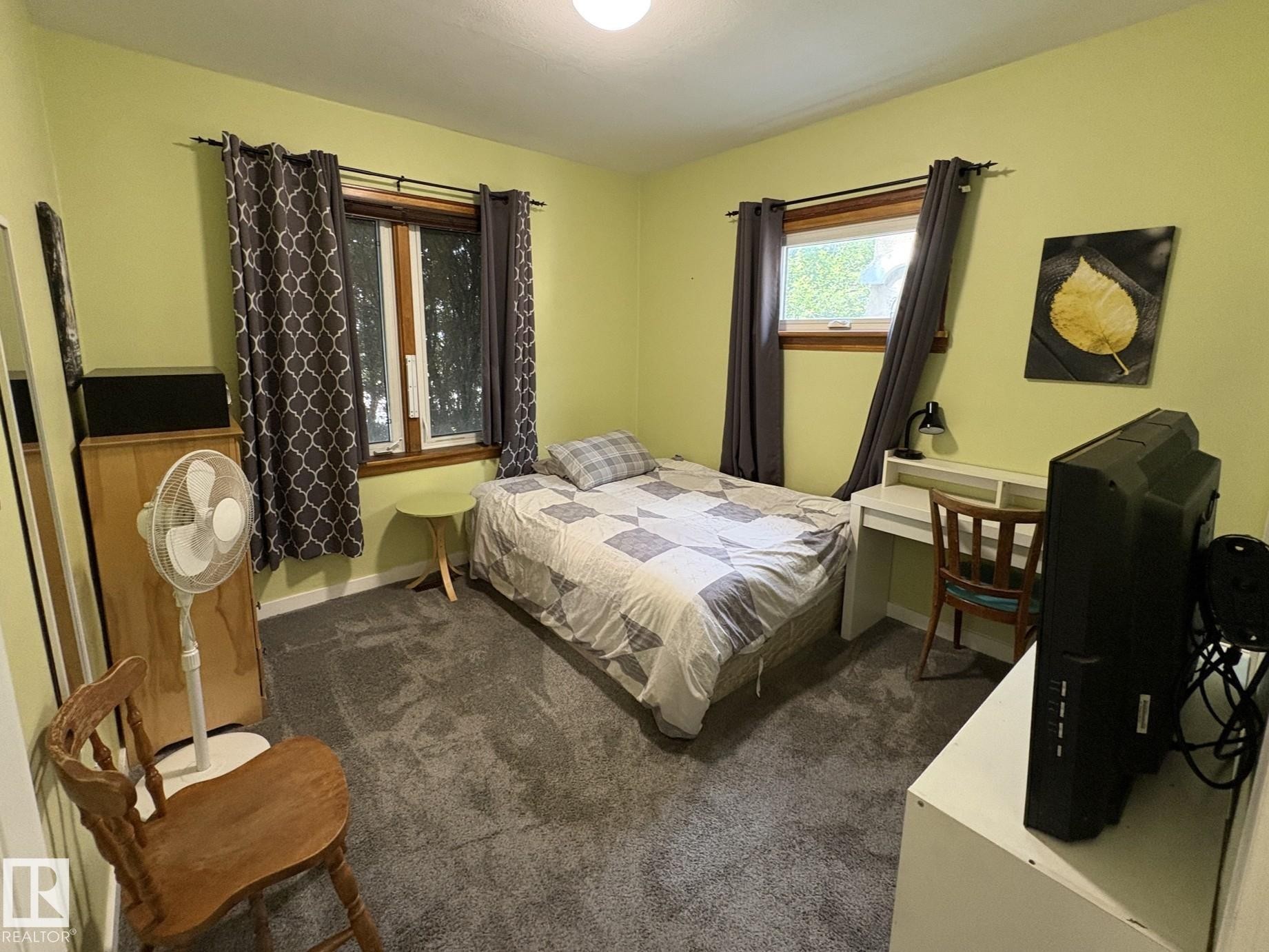 Carpeted room featuring two windows with wood trim, a built-in light fixture, and light-toned walls - 11511 101 Street, Edmonton, AB
