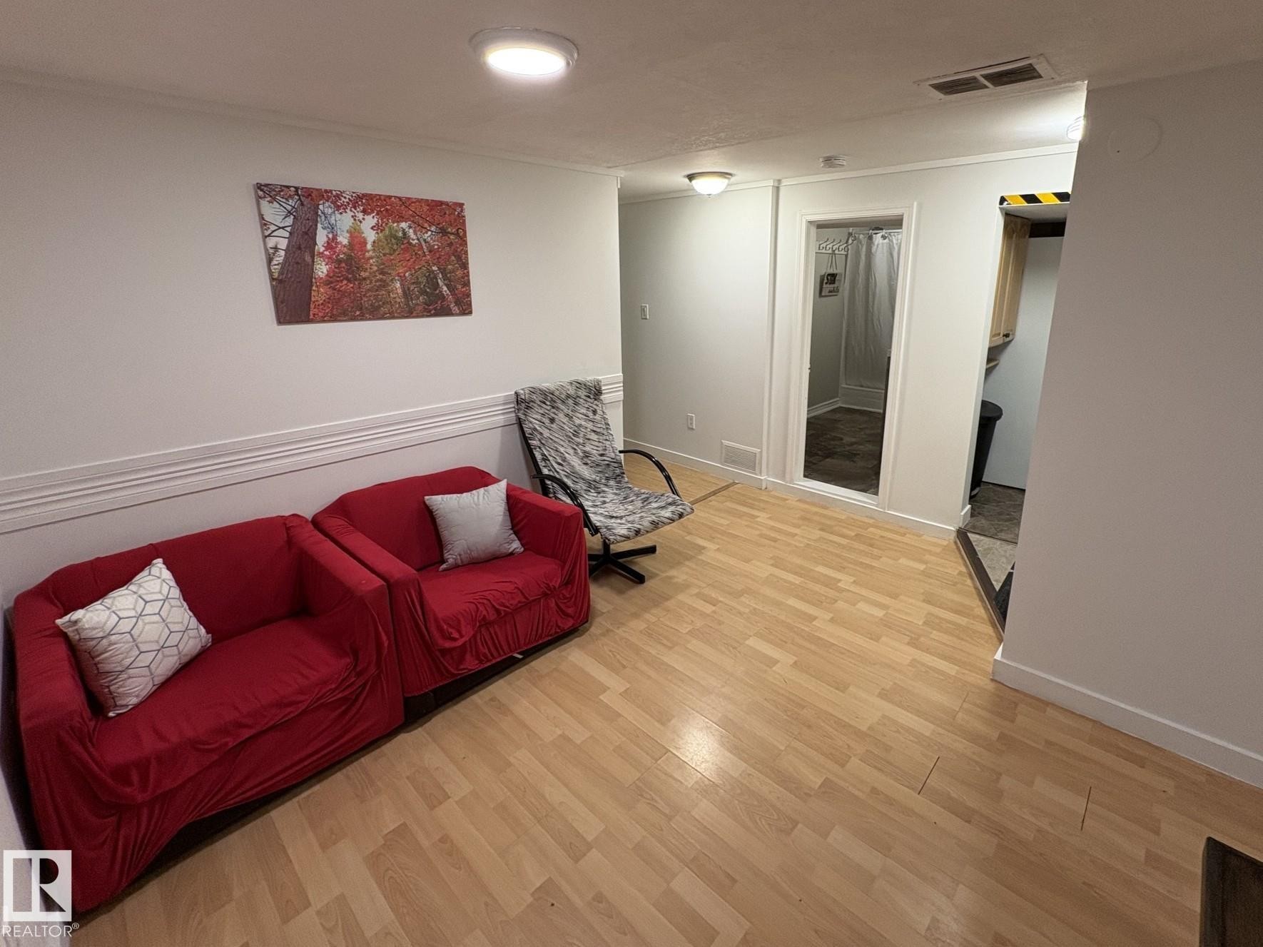 Wood-finish flooring throughout, featuring recessed lighting and a doorway opening to a tiled area - 11511 101 Street, Edmonton, AB