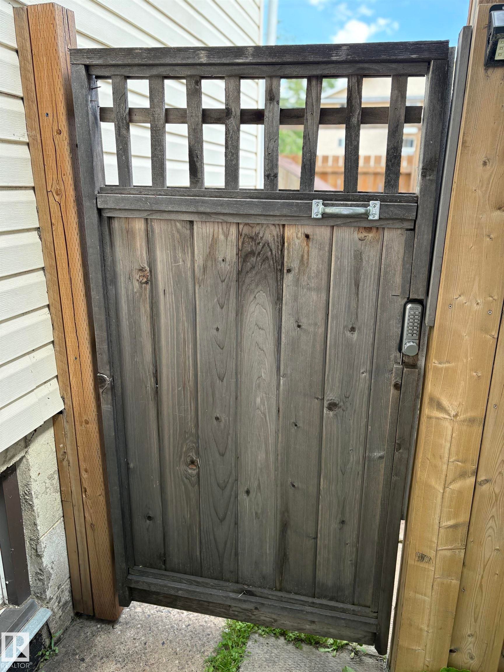 Wood-paneled pedestrian gate with an integrated lattice top and digital keypad entry - 11511 101 Street, Edmonton, AB
