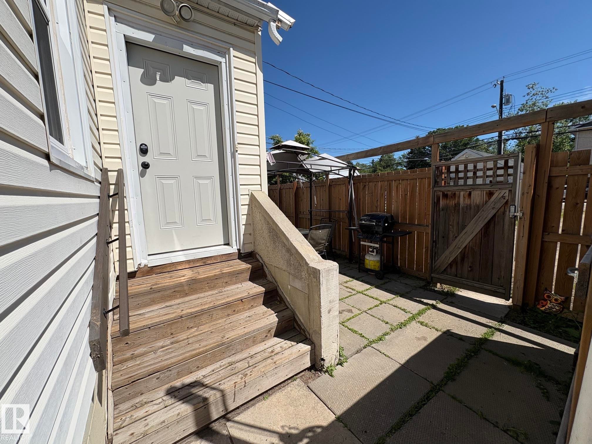 Exterior access door with panel detailing, leading to a concrete paver patio - 11511 101 Street, Edmonton, AB