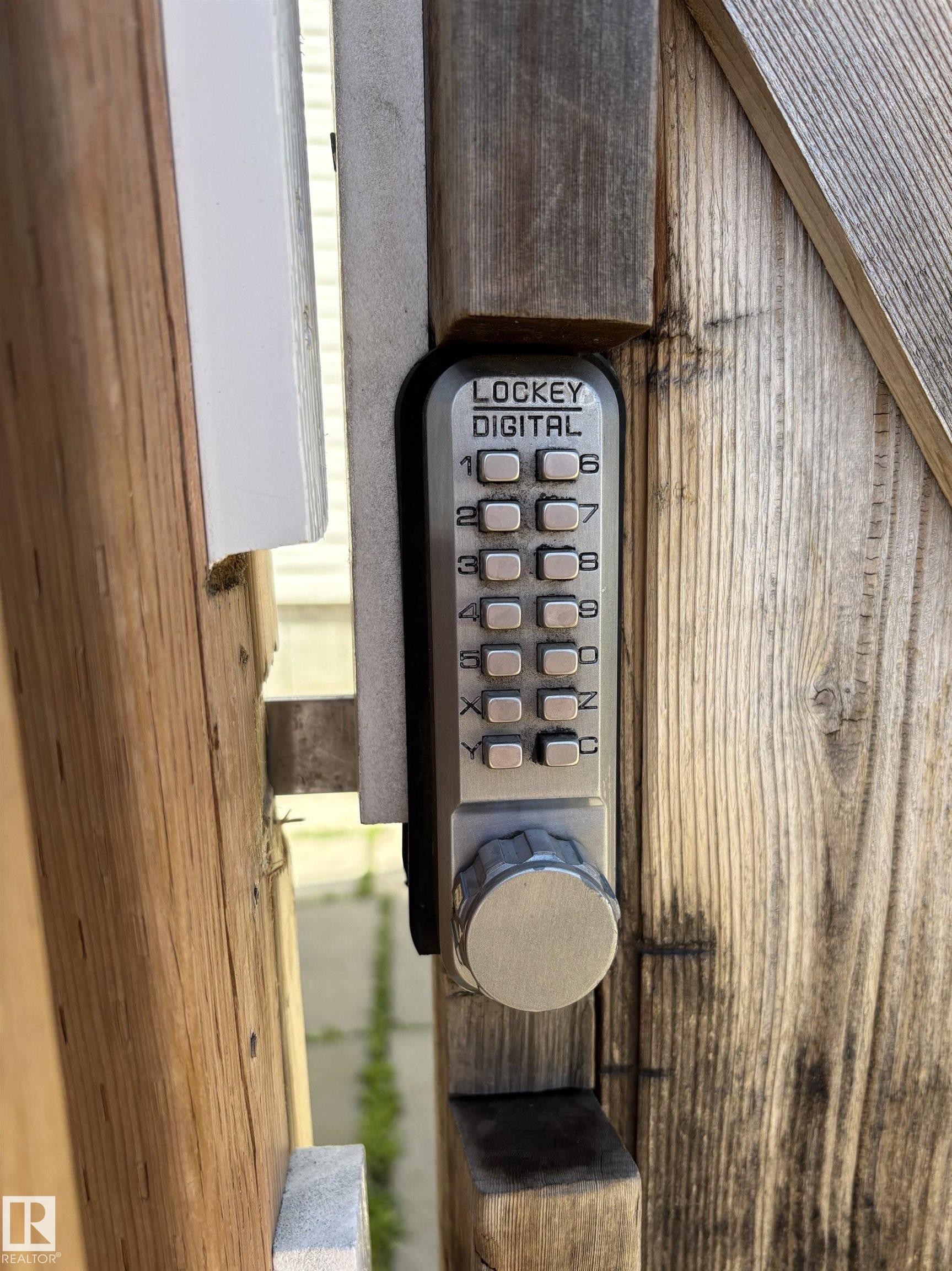 Digital keypad entry system installed on a weathered wood gate - 11511 101 Street, Edmonton, AB