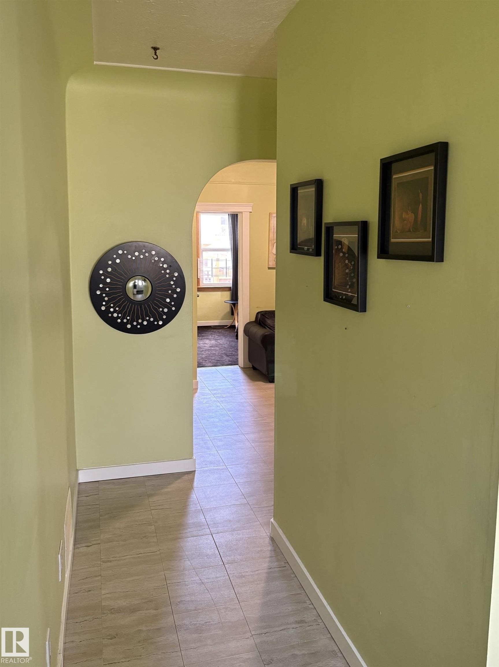 Hallway featuring a tiled floor, light green wall paint, and an arched doorway - 11511 101 Street, Edmonton, AB