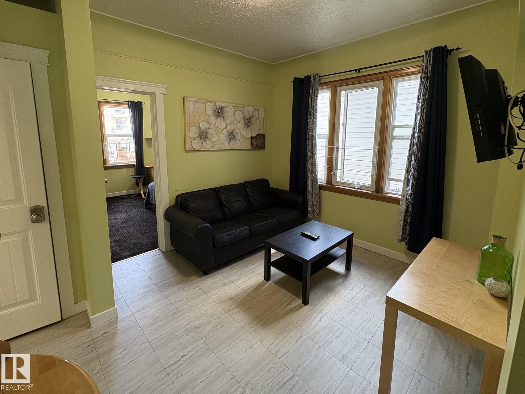 Living area featuring wood-finish flooring and light green walls - 11511 101 Street, Edmonton, AB