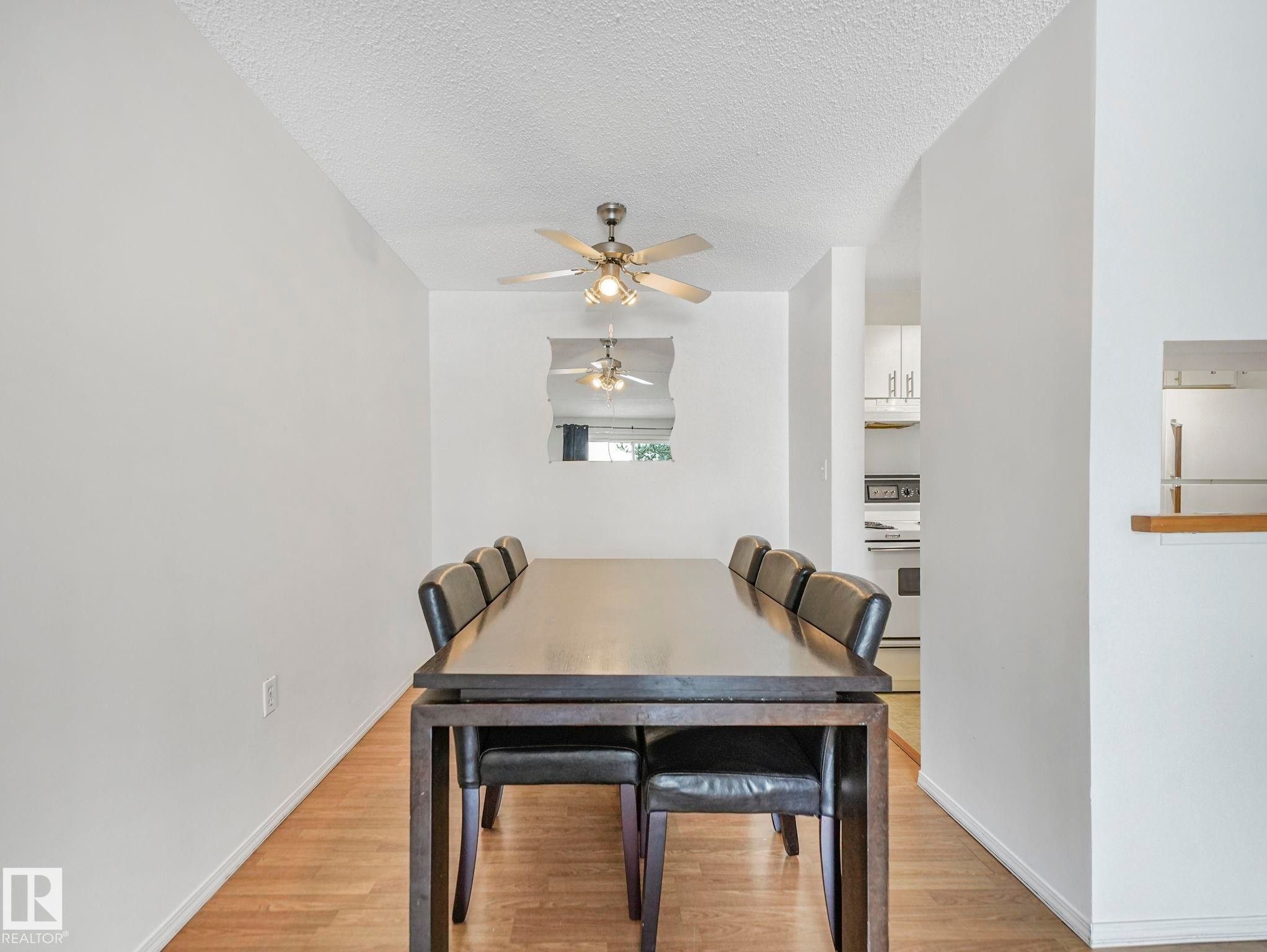 Dining area featuring wood-finish flooring and a ceiling fan - #143 10636 120 St Nw, Edmonton, AB - Indoor Photo Showing Dining Room