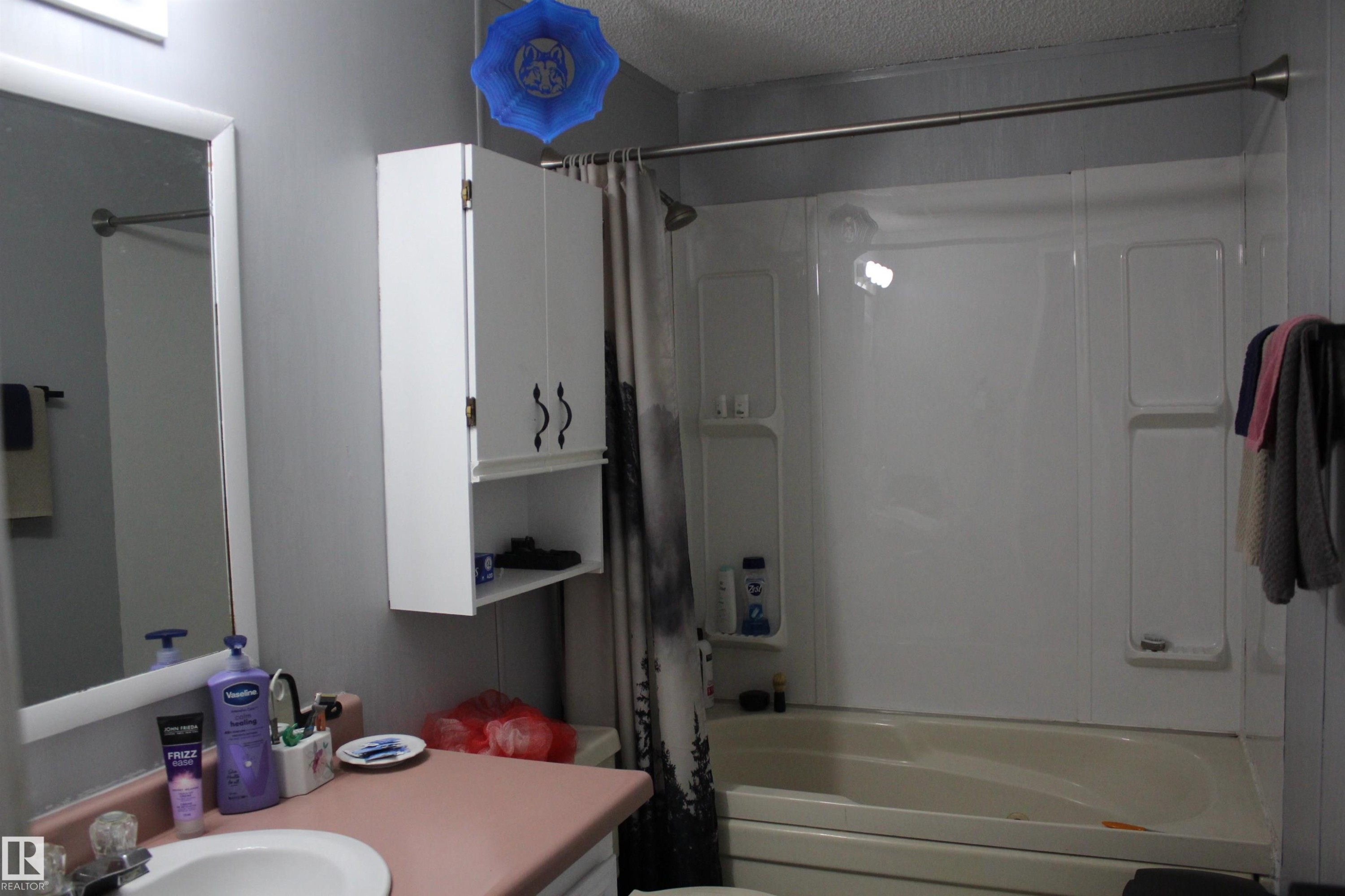 Bathroom featuring a white vanity with a rectangular sink, a pink countertop, and a wall-mounted mirror - 4839 49 Avenue, Chipman, AB