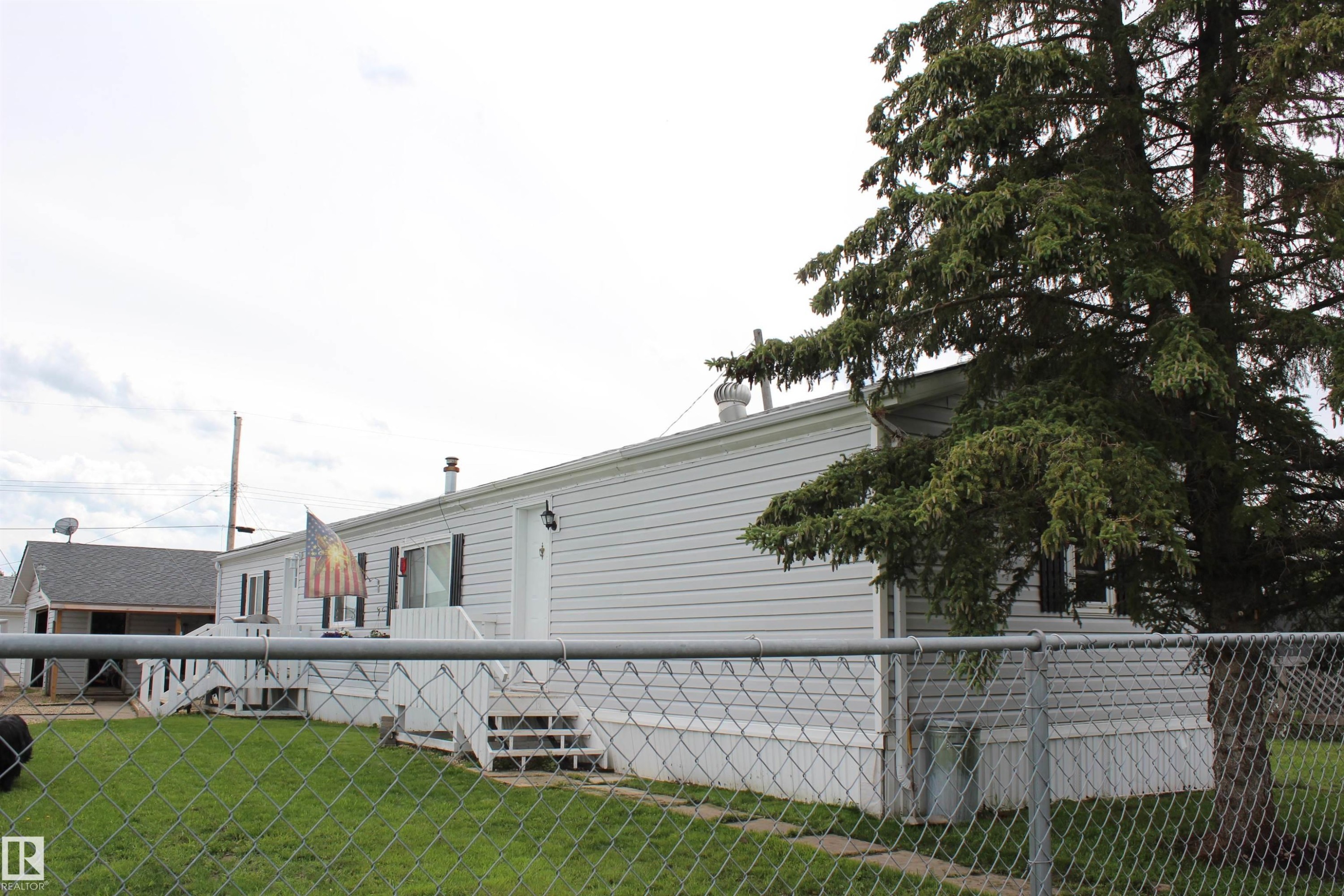 White siding exterior with multiple windows featuring black shutters - 4839 49 Avenue, Chipman, AB