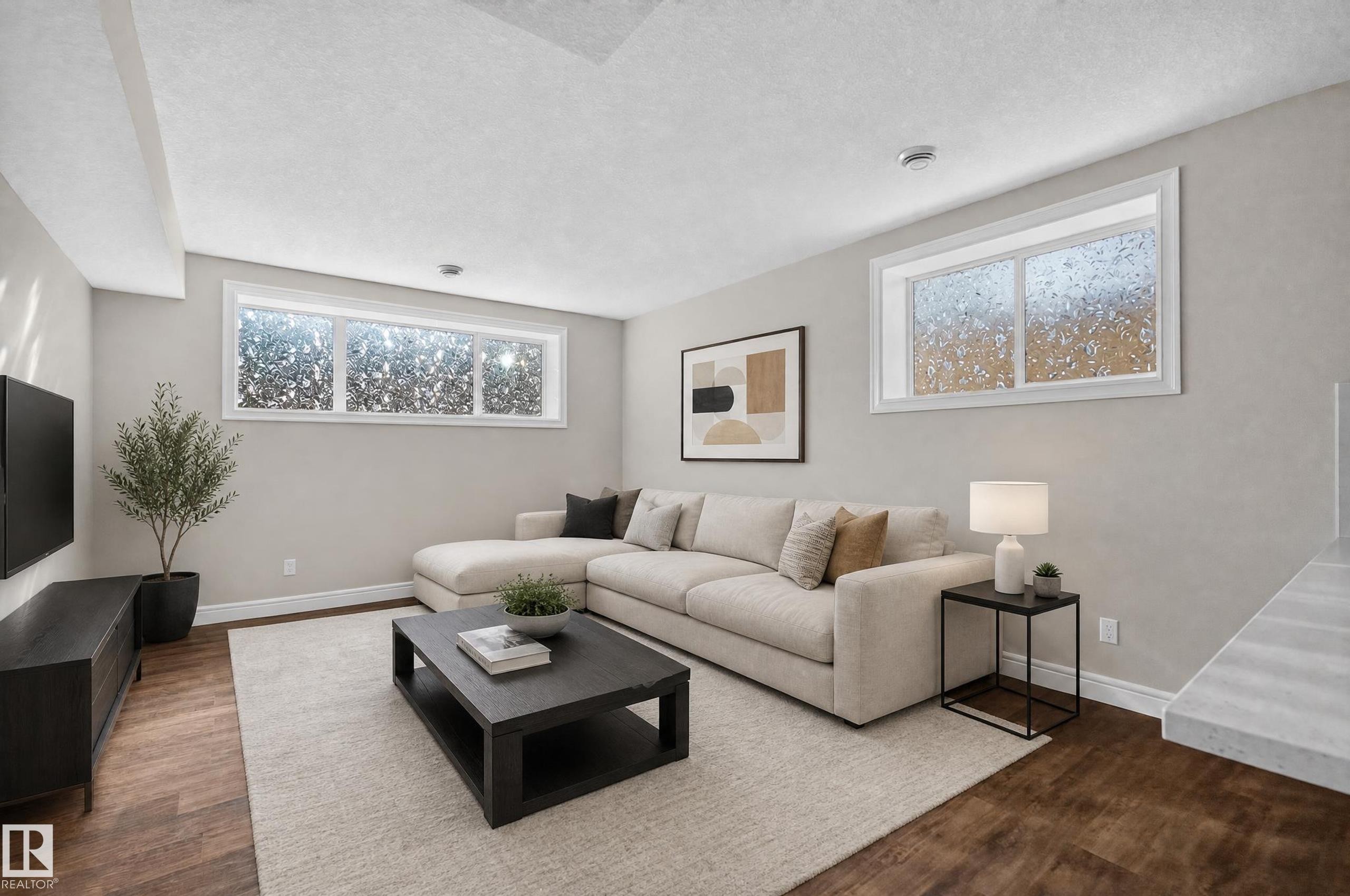 Living area featuring wood-finish flooring, light-toned walls, and white trim - 1346 Cunningham Drive, Edmonton, AB