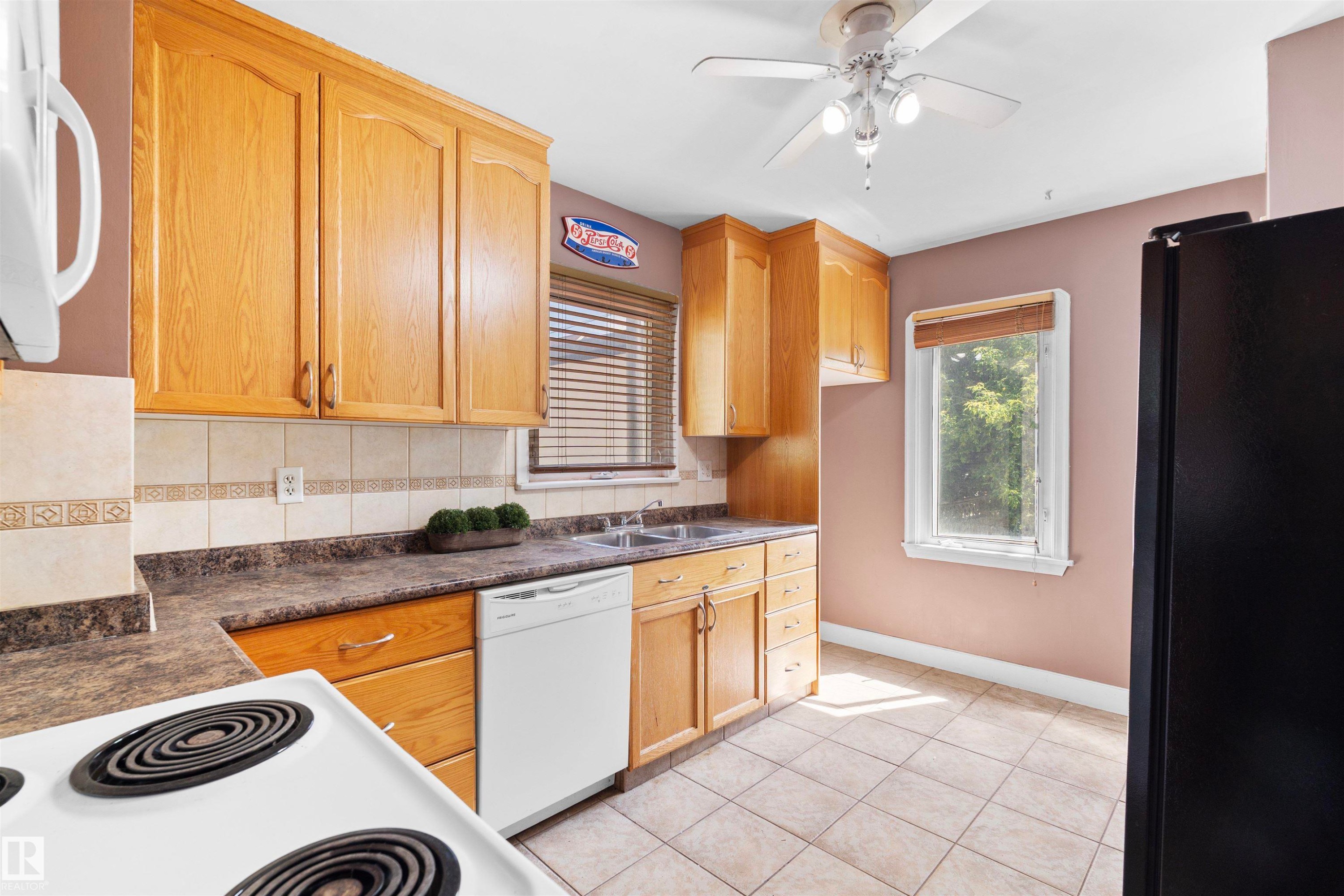 Kitchen featuring wood-finish cabinetry, tile flooring, and a window with blinds - 10607 73 Ave, Edmonton, AB