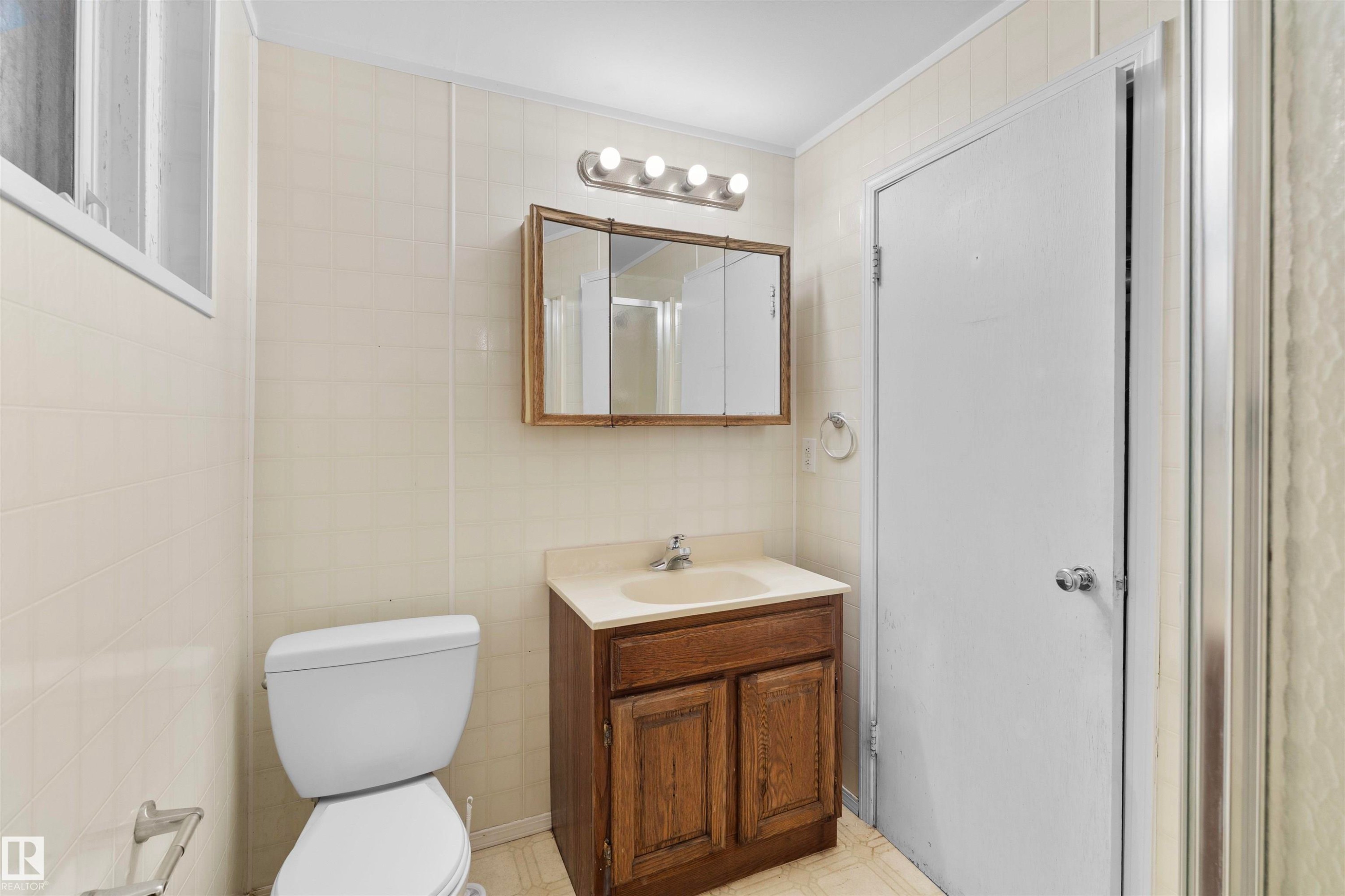 Bathroom featuring a single vanity with wood-finish cabinetry and integrated sink - 10607 73 Ave, Edmonton, AB