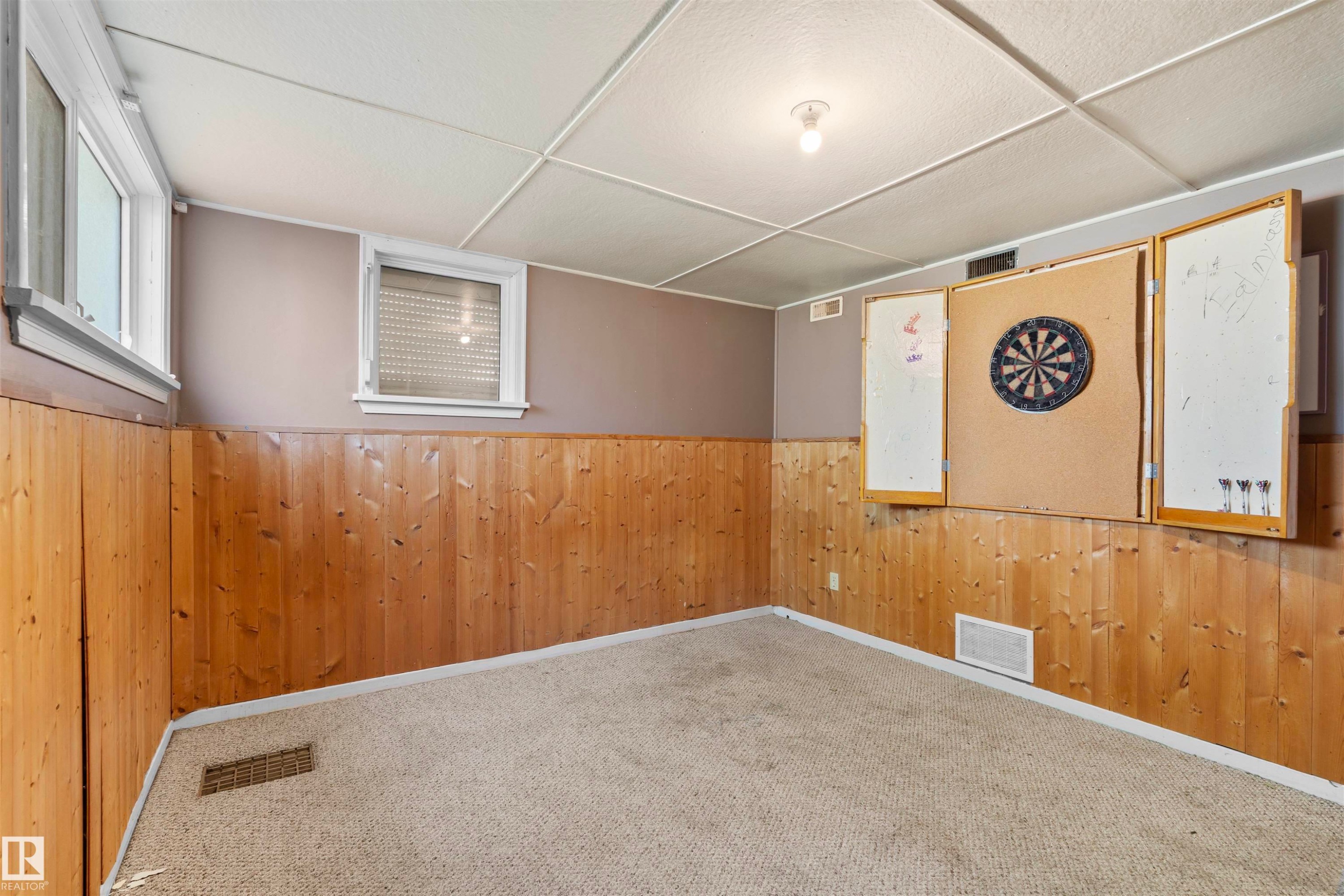 Finished lower level space featuring carpet flooring, wood panel wainscoting, painted upper walls, and a drop ceiling with recessed lighting - 10607 73 Ave, Edmonton, AB