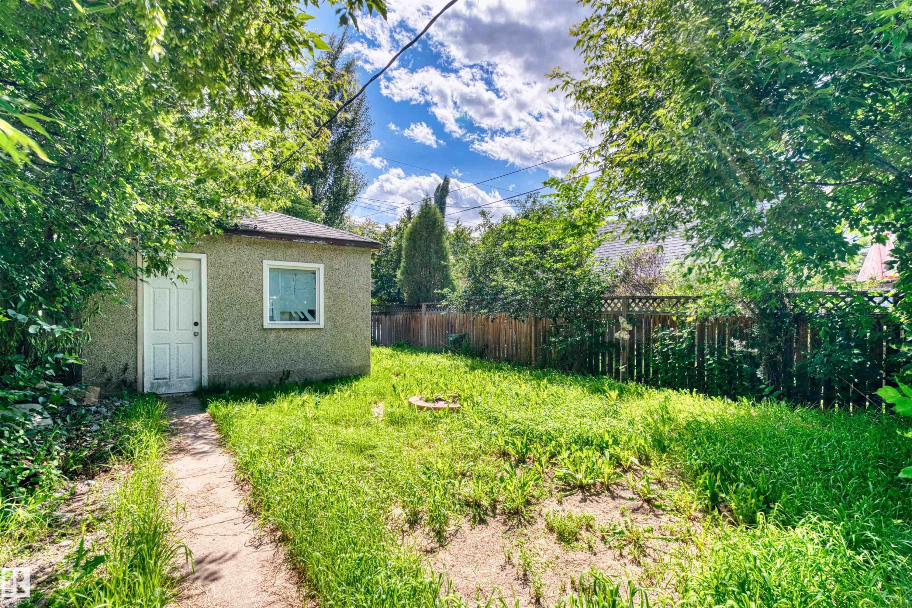 Detached accessory building featuring textured stucco siding and a white-framed window - 10607 73 Ave, Edmonton, AB