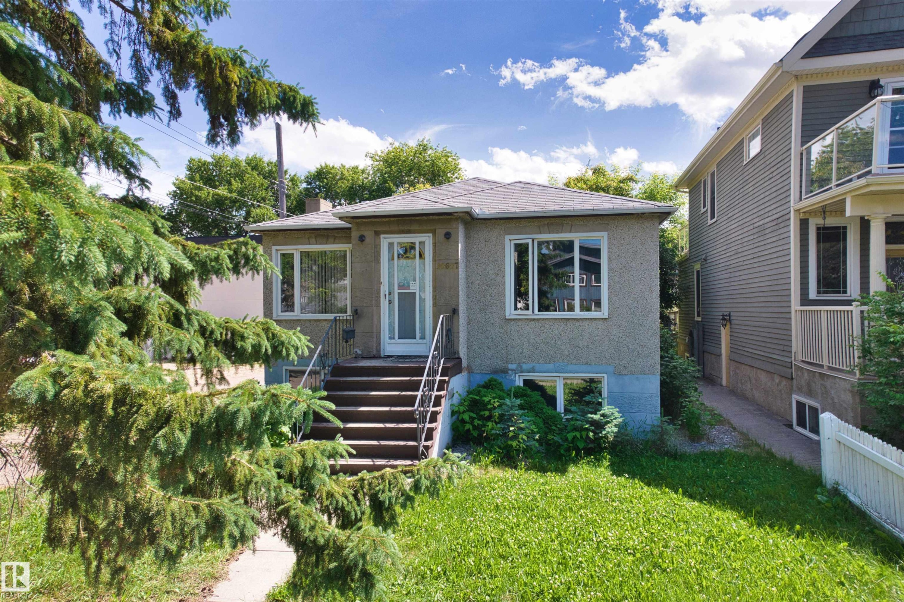 Stucco exterior featuring a gabled roofline and multiple windows - 10607 73 Ave, Edmonton, AB