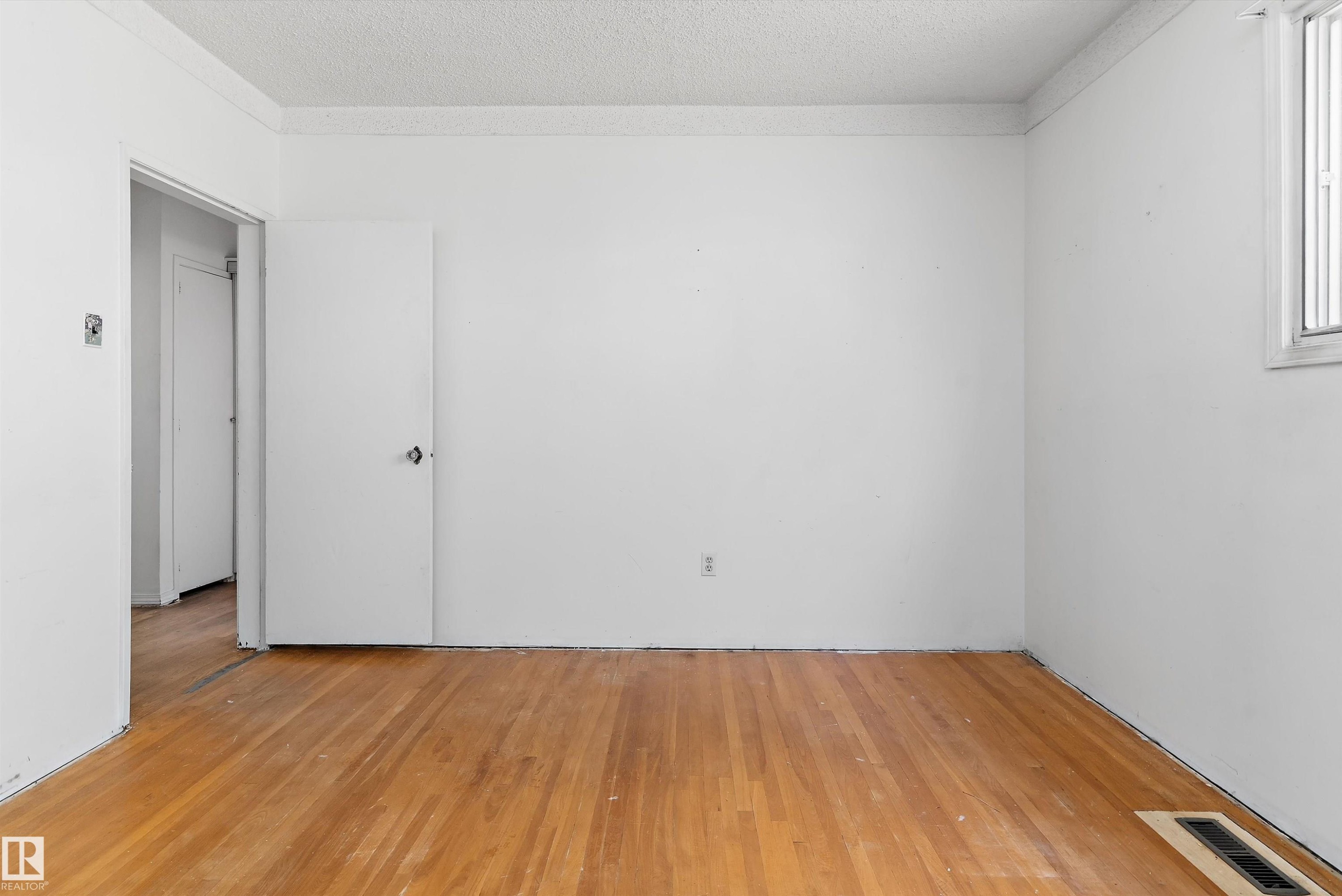 Room with wood-finish flooring, white painted walls, and a window for natural light - 11619 123 Street, Edmonton, AB