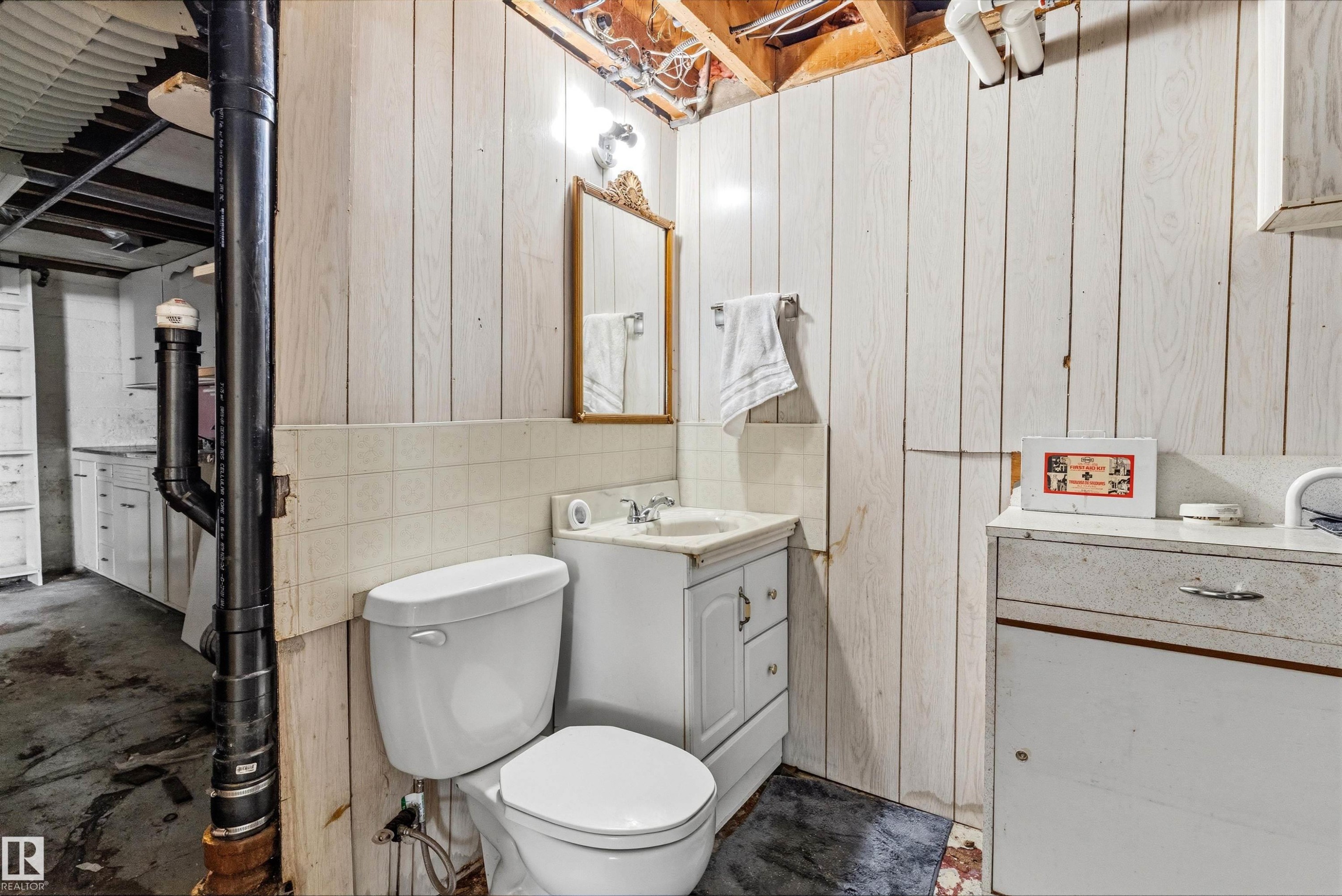 Bathroom featuring a white toilet, white vanity with integrated sink, and a framed mirror - 11619 123 Street, Edmonton, AB