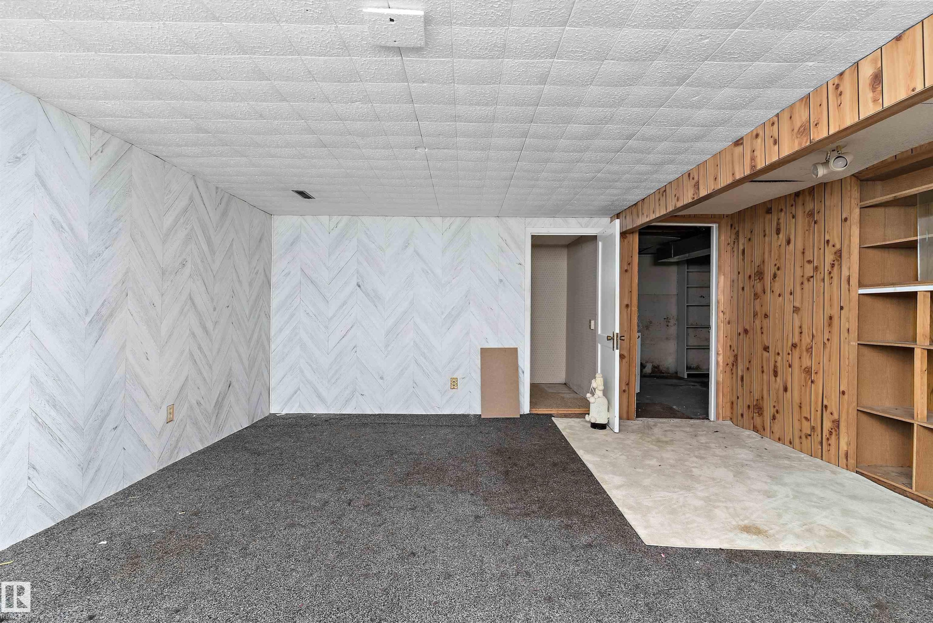 Interior space featuring a patterned wall finish, a textured drop ceiling, and mixed flooring - 11619 123 Street, Edmonton, AB