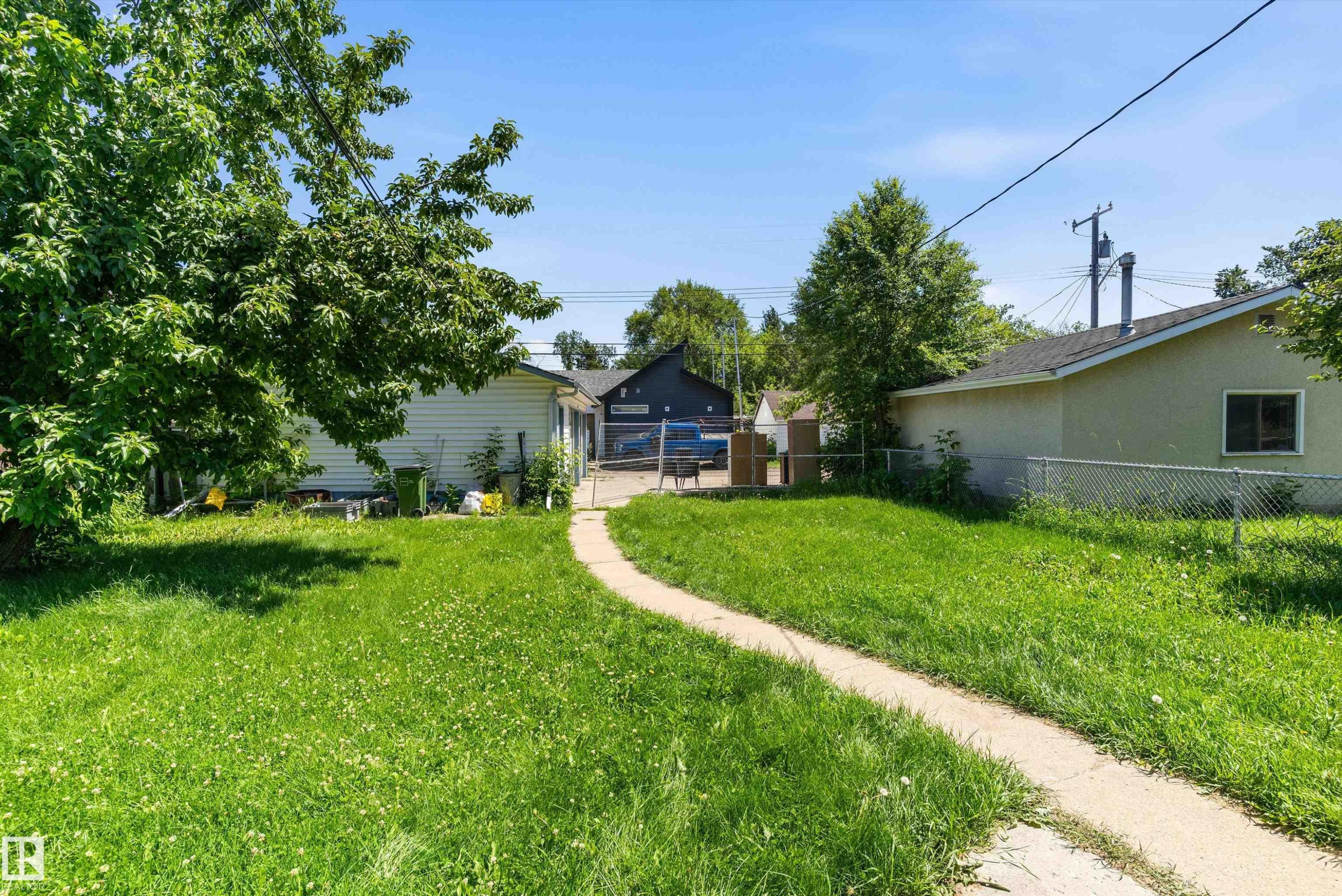 Expansive green lawn with a curved concrete pathway leading to the rear of the property - 11619 123 Street, Edmonton, AB