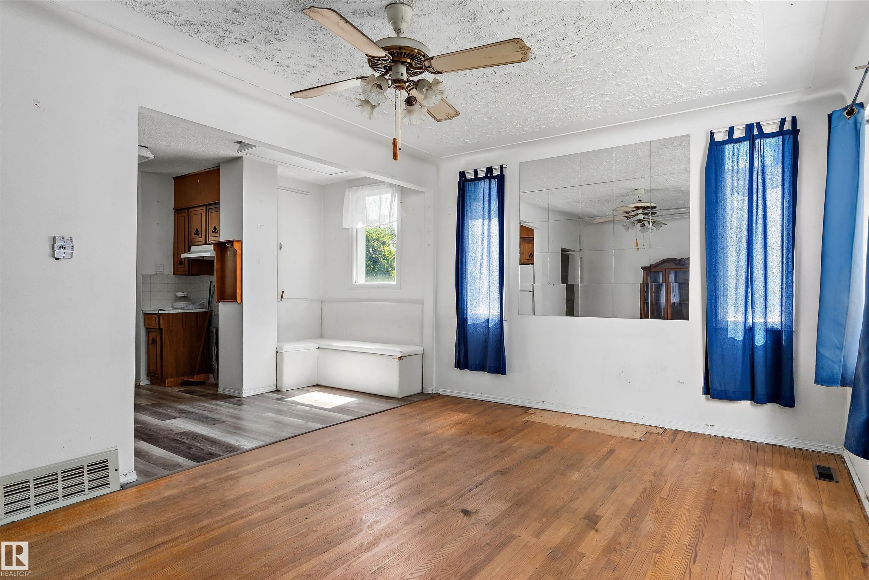 Expansive living area featuring hardwood flooring, a ceiling fan with light fixture, and a built-in bench seating area - 11619 123 Street, Edmonton, AB