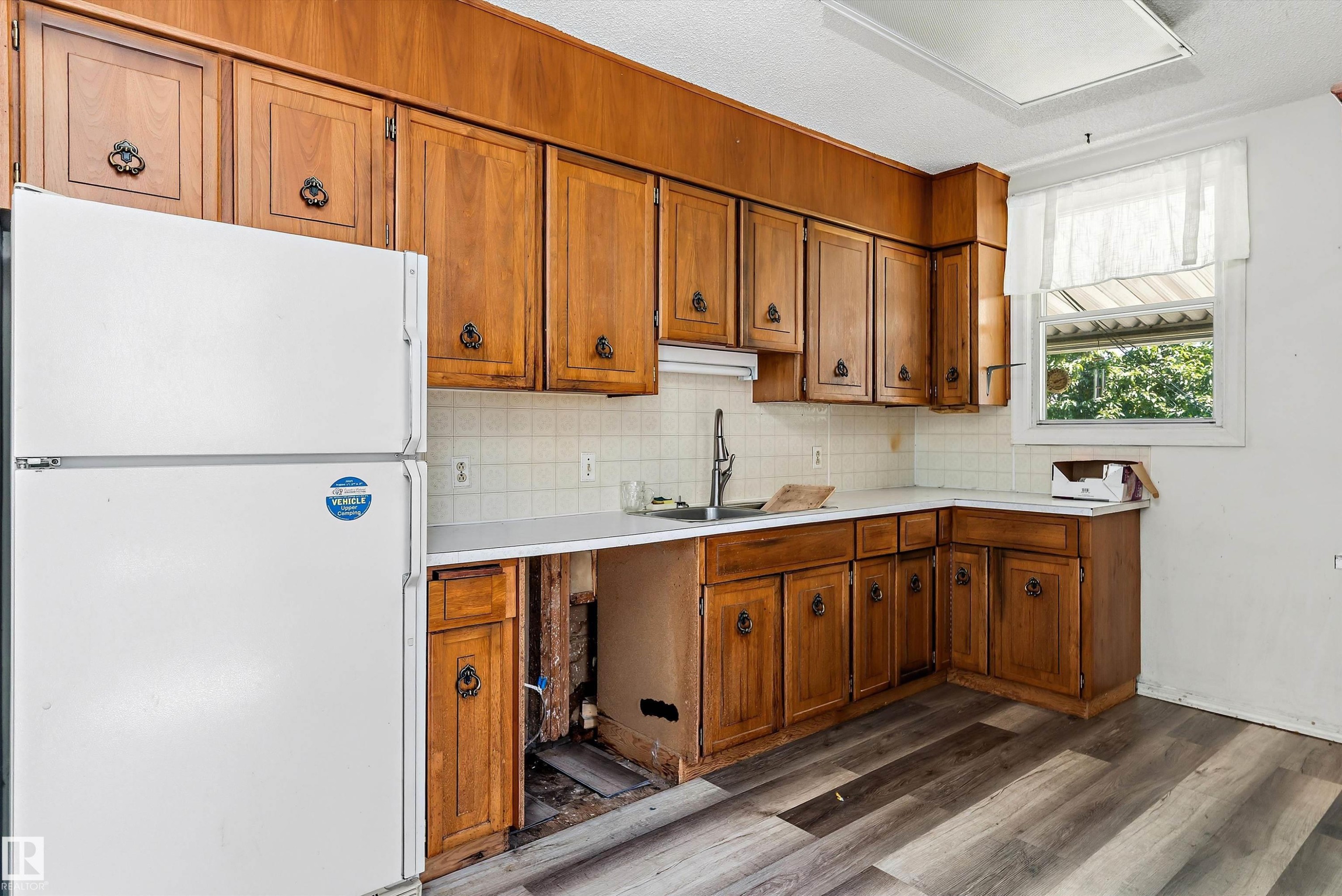 Kitchen featuring wood cabinetry, light countertops, and a tile backsplash - 11619 123 Street, Edmonton, AB