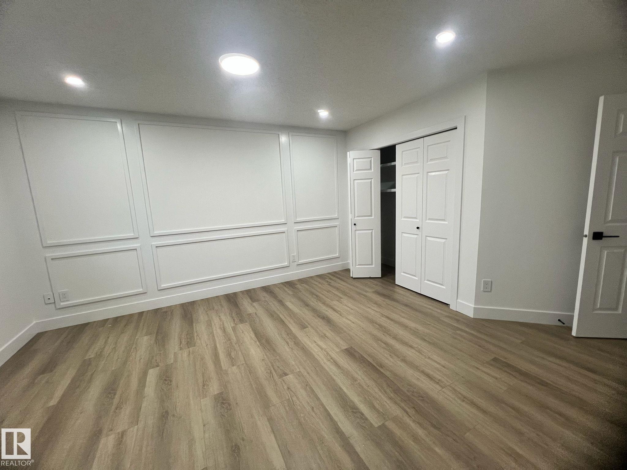 Spacious room featuring wood-finish flooring and recessed lighting - 3320 43 Street, Edmonton, AB
