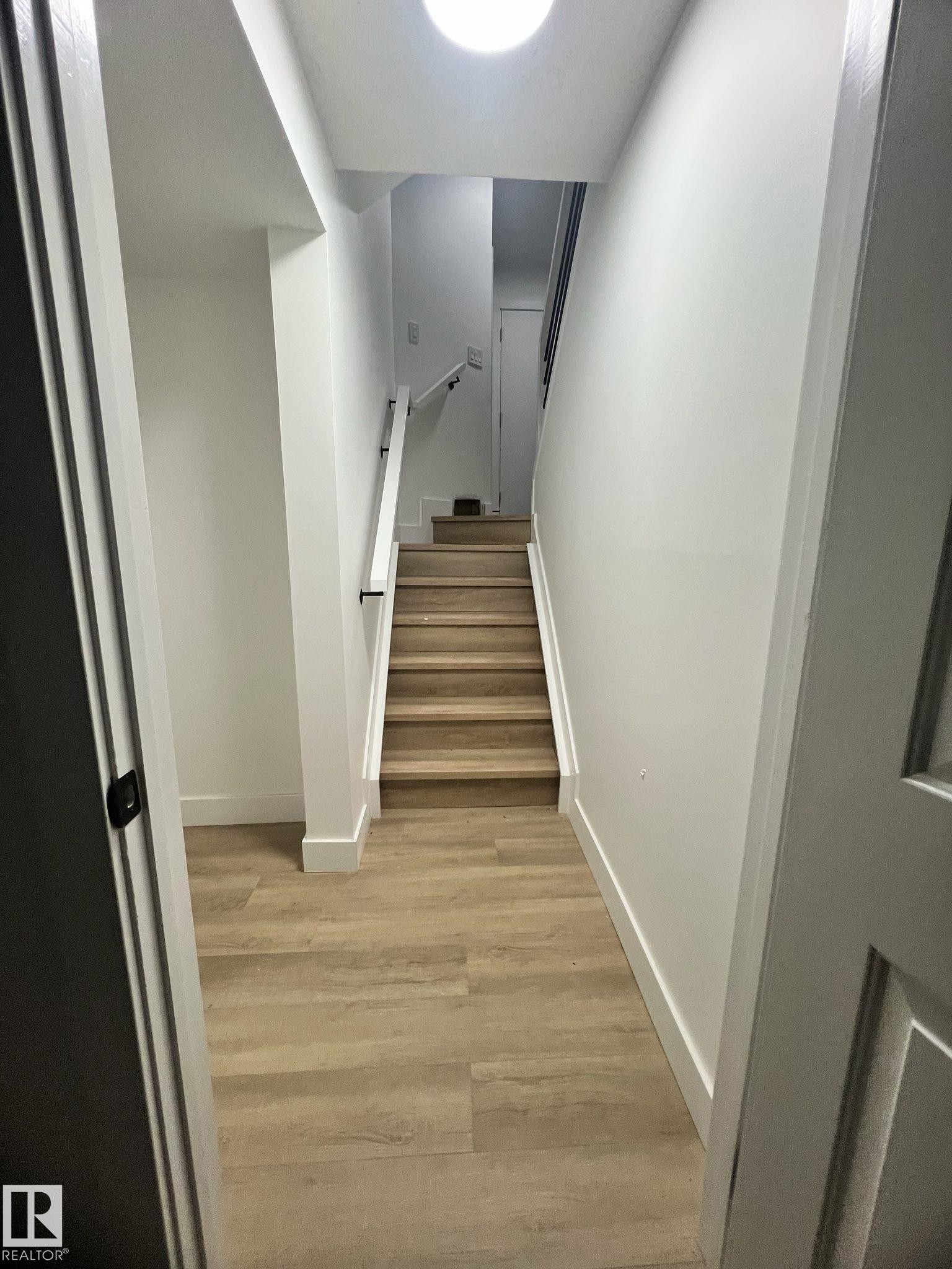 Interior staircase with wood-finish treads and risers, complemented by a white handrail with black supports - 3320 43 Street, Edmonton, AB