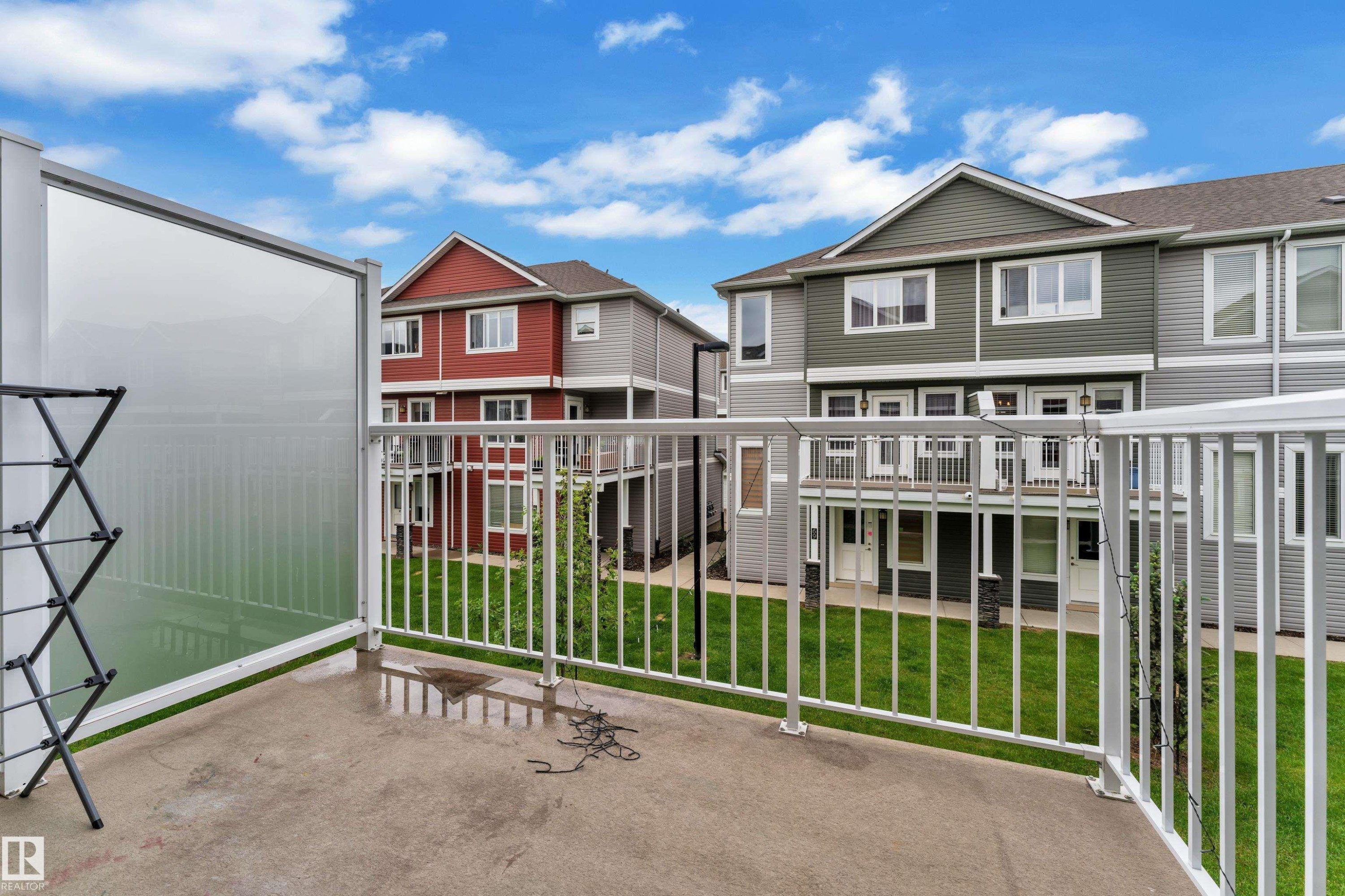 Private concrete balcony with white metal railing and translucent privacy panel - #82 1816 Rutherford Rd Sw, Edmonton, AB - Outdoor