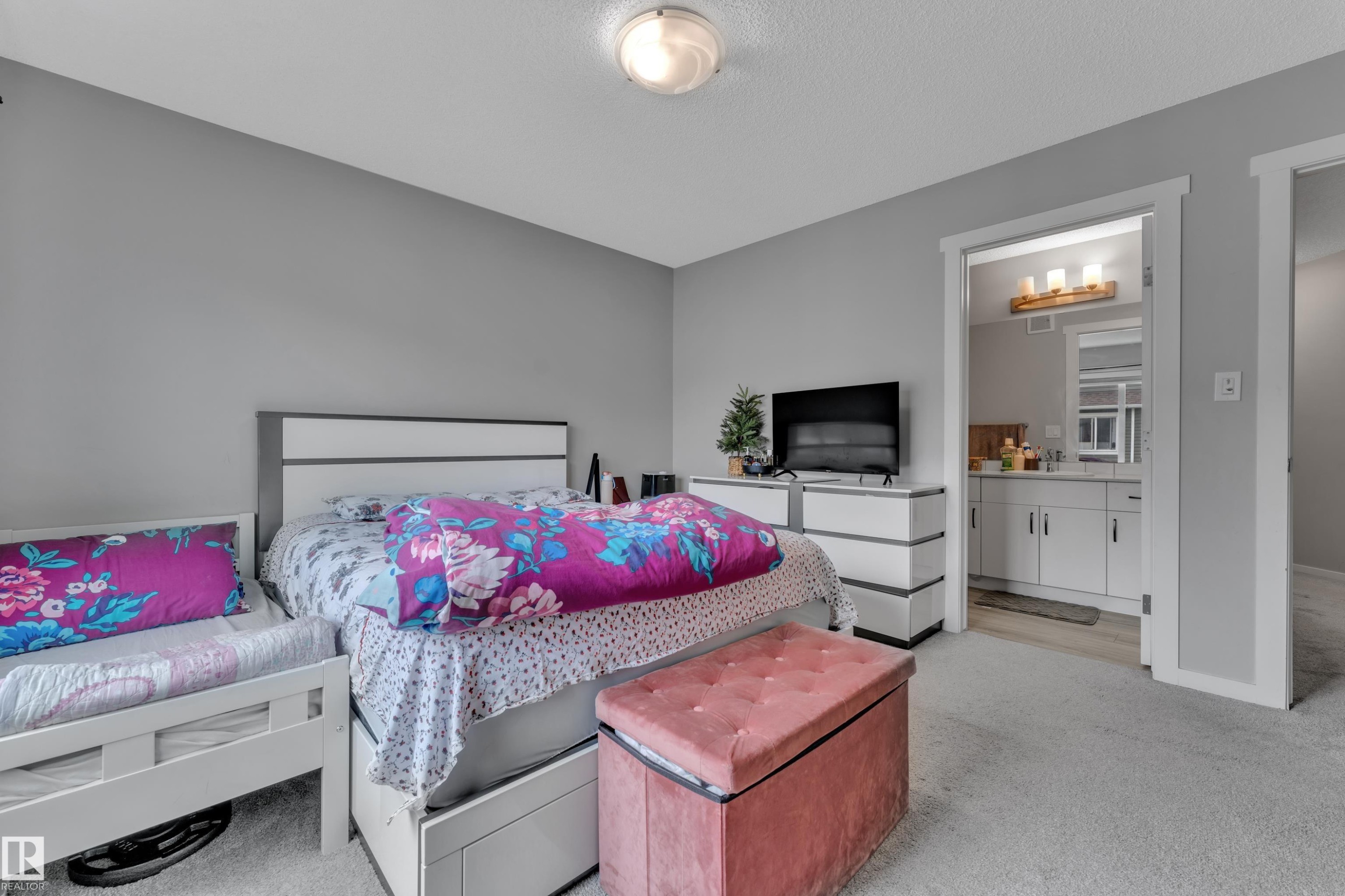 Spacious bedroom featuring light gray walls and plush carpeting, with direct access to a private bathroom - #82 1816 Rutherford Rd Sw, Edmonton, AB - Indoor Photo Showing Bedroom
