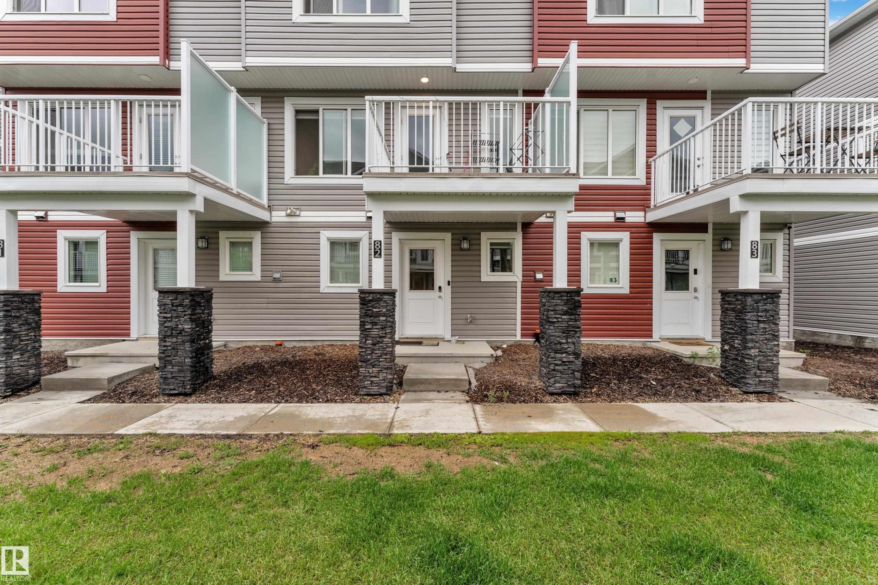 Multi-level townhome exterior featuring red and gray siding - #82 1816 Rutherford Rd Sw, Edmonton, AB - Outdoor With Facade