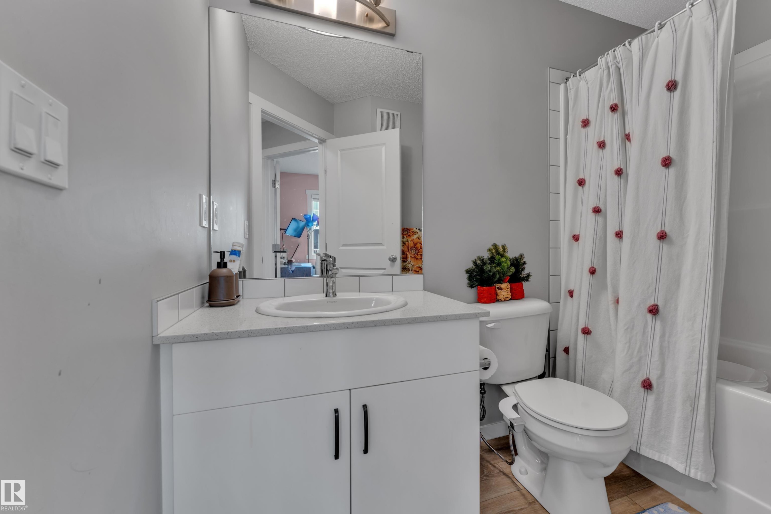 Bathroom featuring a white vanity with integrated sink, chrome faucet, and a large wall-mounted mirror - #82 1816 Rutherford Rd Sw, Edmonton, AB - Indoor Photo Showing Bathroom
