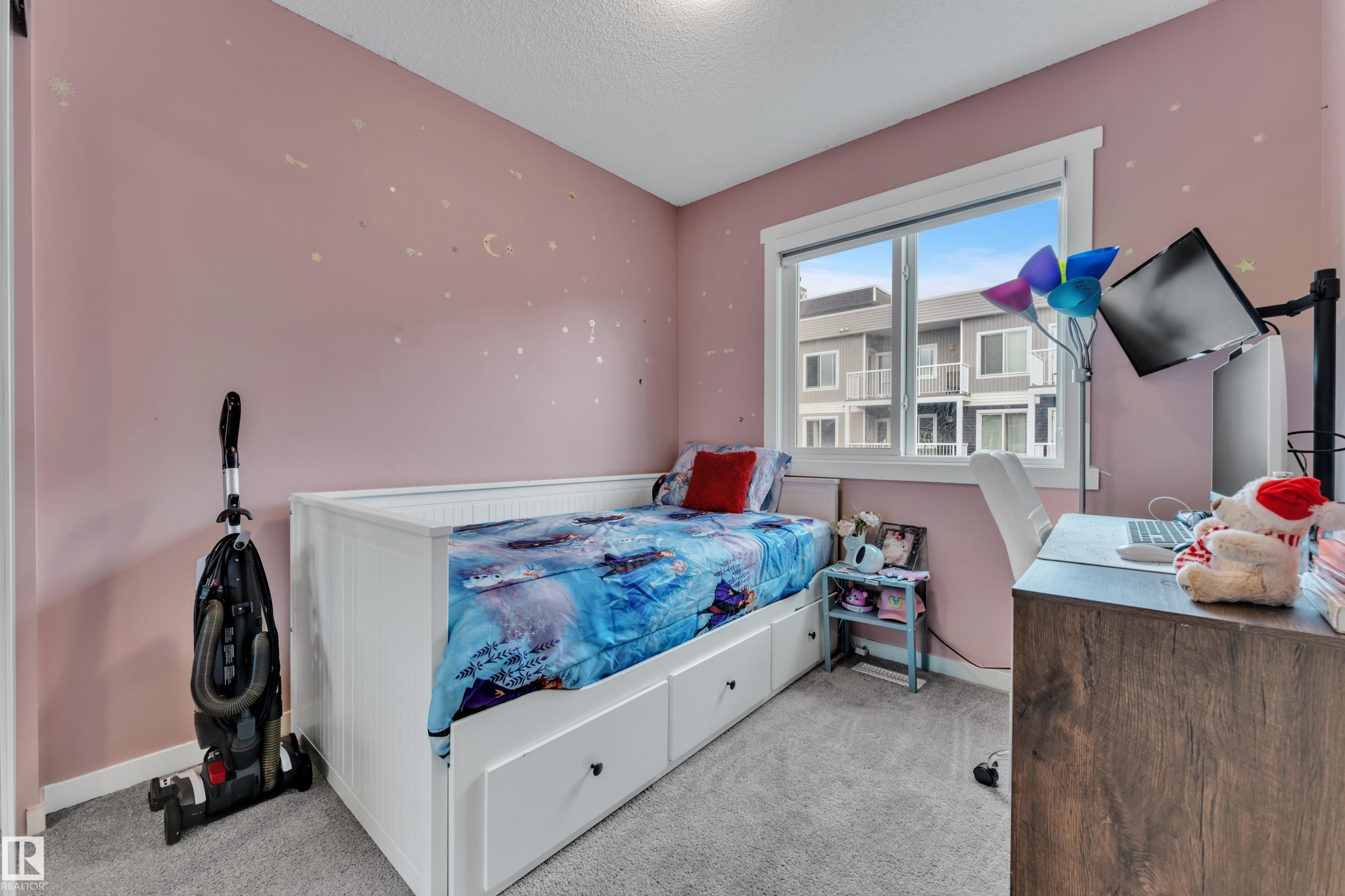 Light-filled interior space featuring a large window, plush carpet flooring, and a built-in bed frame with integrated storage drawers - #82 1816 Rutherford Rd Sw, Edmonton, AB - Indoor Photo Showing Bedroom