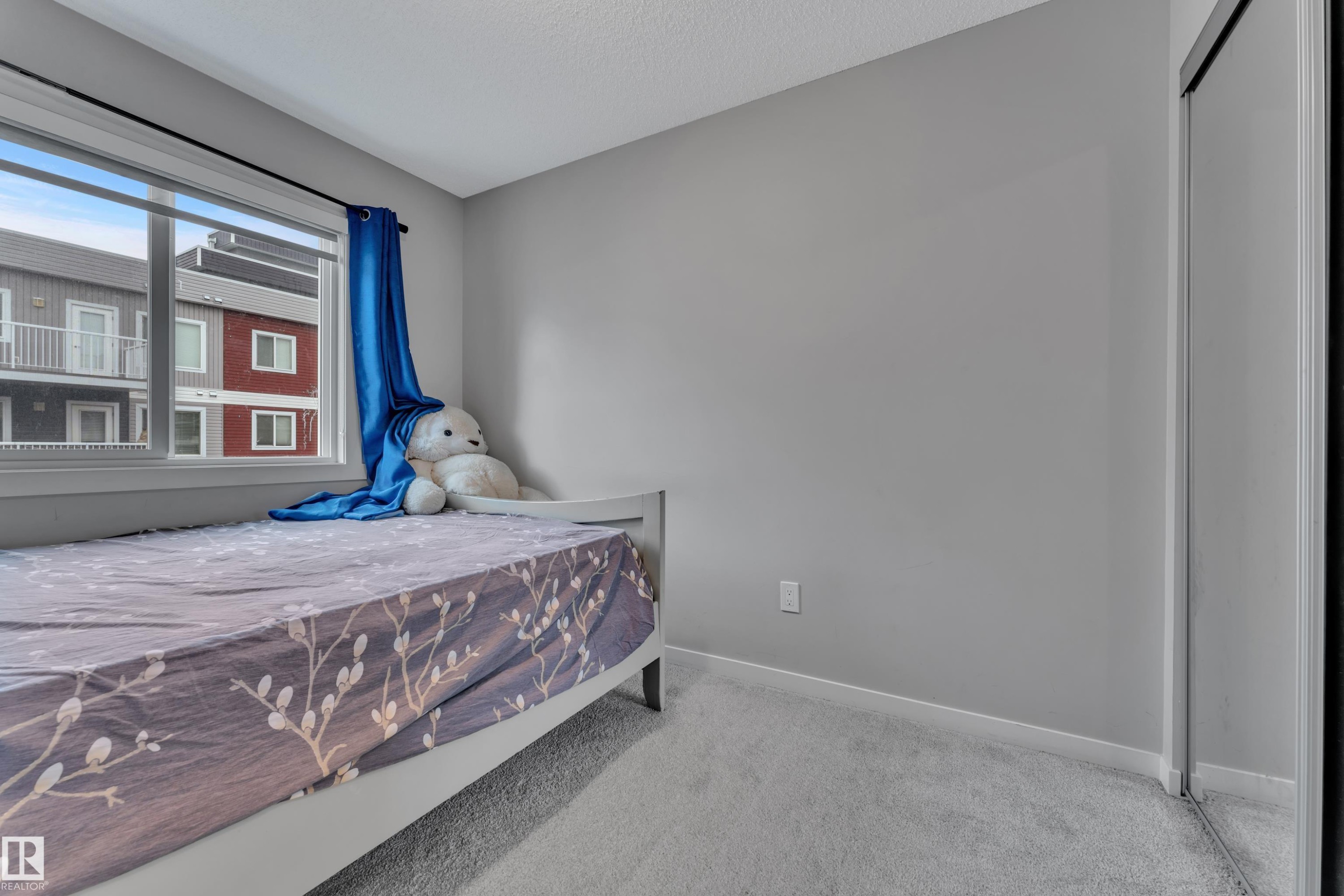 Bright room with a large window and light gray walls - #82 1816 Rutherford Rd Sw, Edmonton, AB - Indoor Photo Showing Bedroom