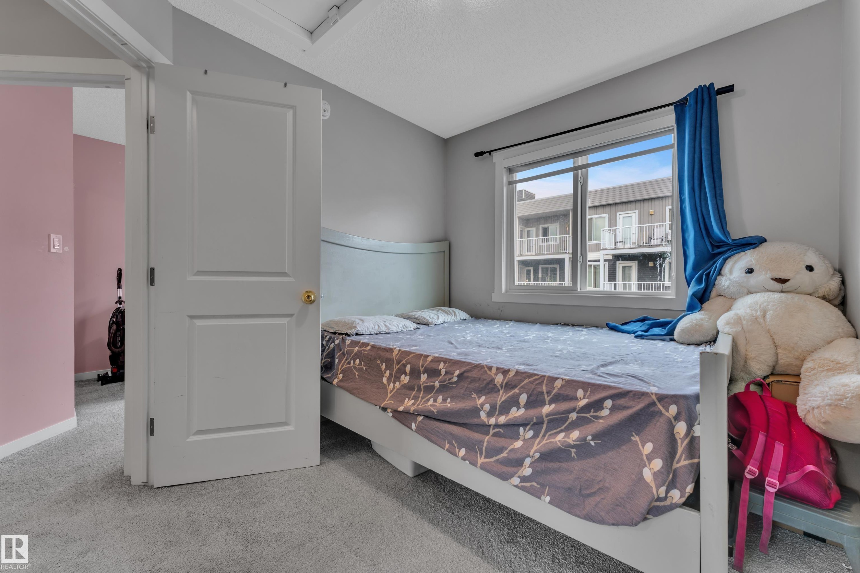 Room featuring light gray walls, plush gray carpeting, and a white interior door with brass hardware - #82 1816 Rutherford Rd Sw, Edmonton, AB - Indoor Photo Showing Bedroom