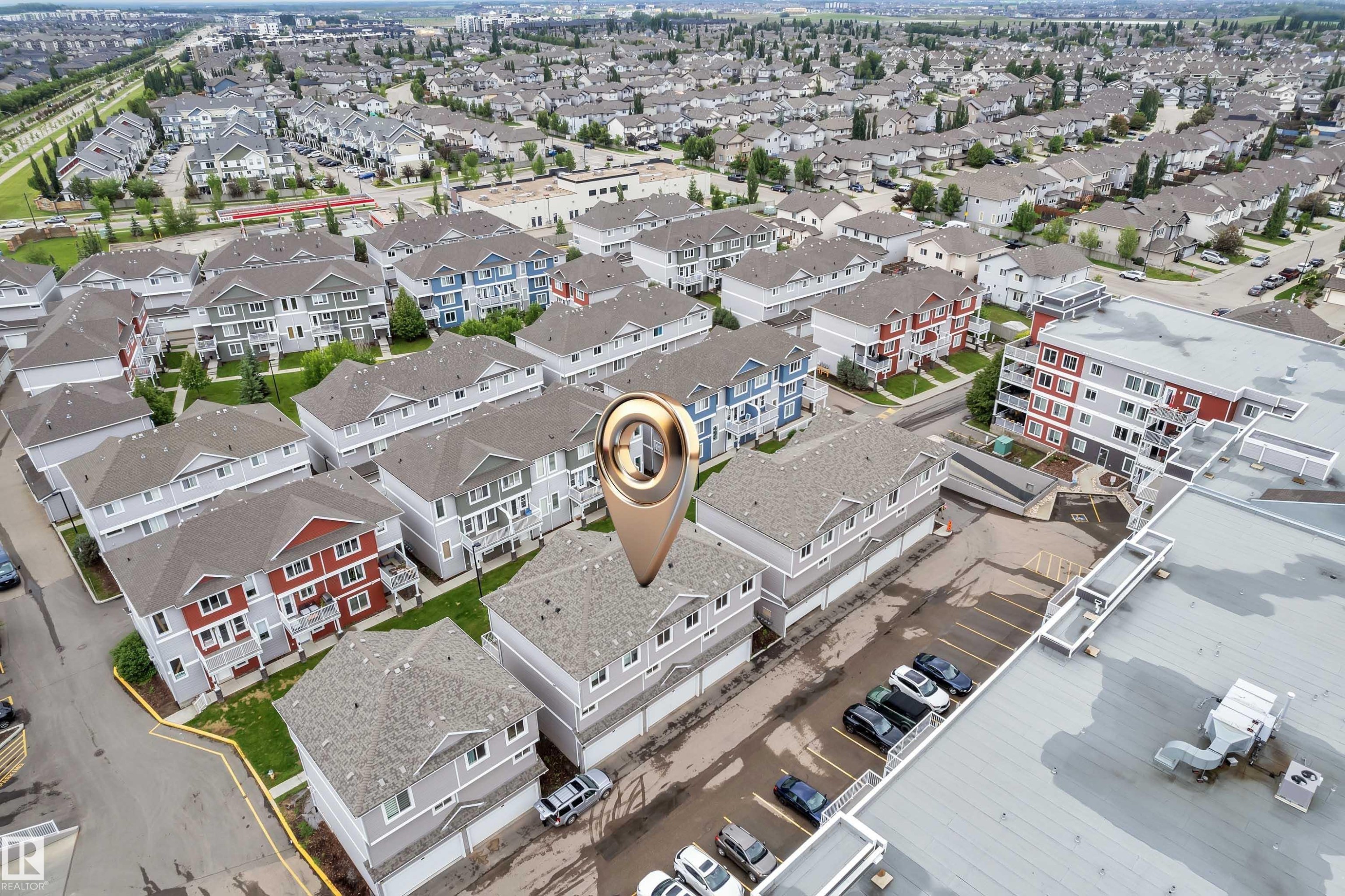 Aerial perspective showcasing a residential community with multi-story townhomes featuring light grey siding and dark roofs - #82 1816 Rutherford Rd Sw, Edmonton, AB - Other