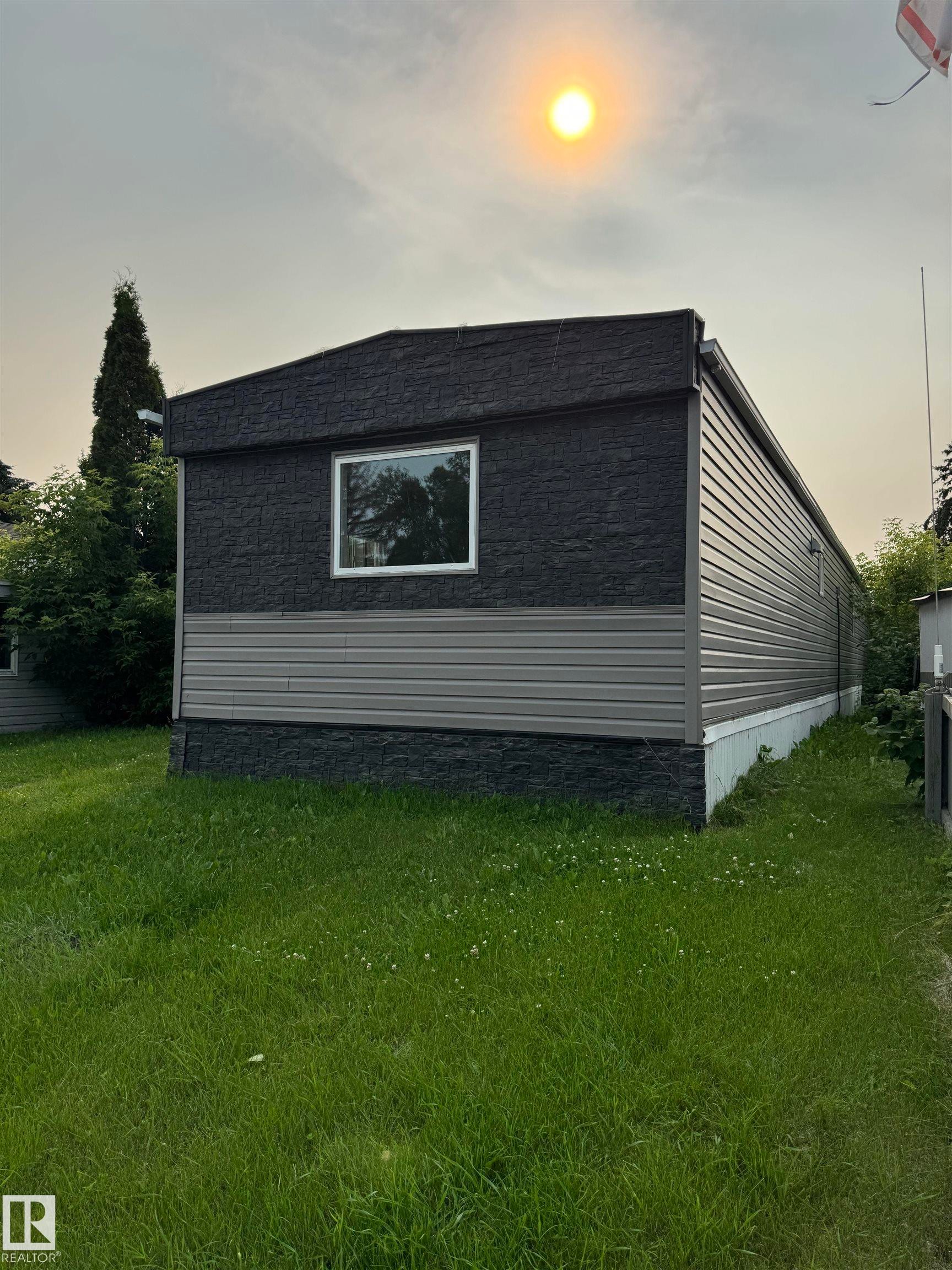 Exterior featuring dark textured siding, light-toned horizontal paneling, and a white-framed window - 543 Evergreen Park Northwest, Edmonton, AB - Outdoor
