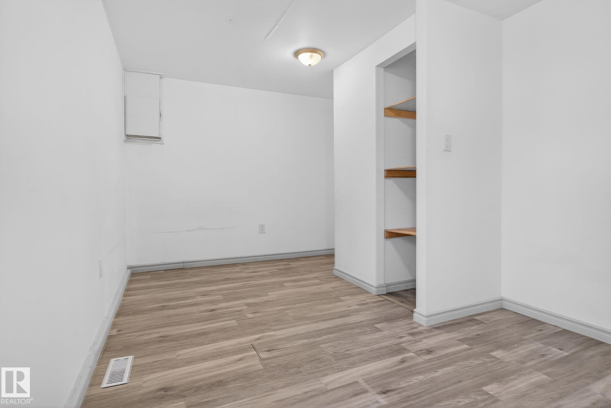 Interior room featuring wood-finish flooring, light-toned walls, and a built-in recessed shelving unit with three wooden shelves - 543 Evergreen Park Northwest, Edmonton, AB - Indoor Photo Showing Other Room